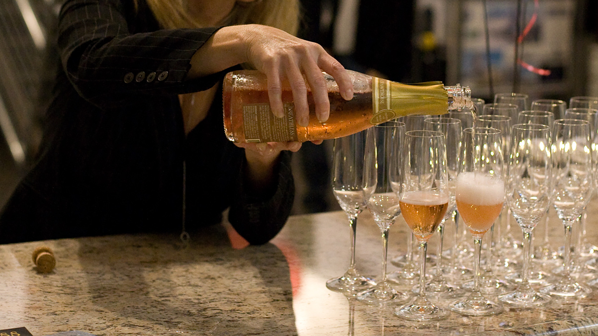 Woman pouring champagne into row of glasses