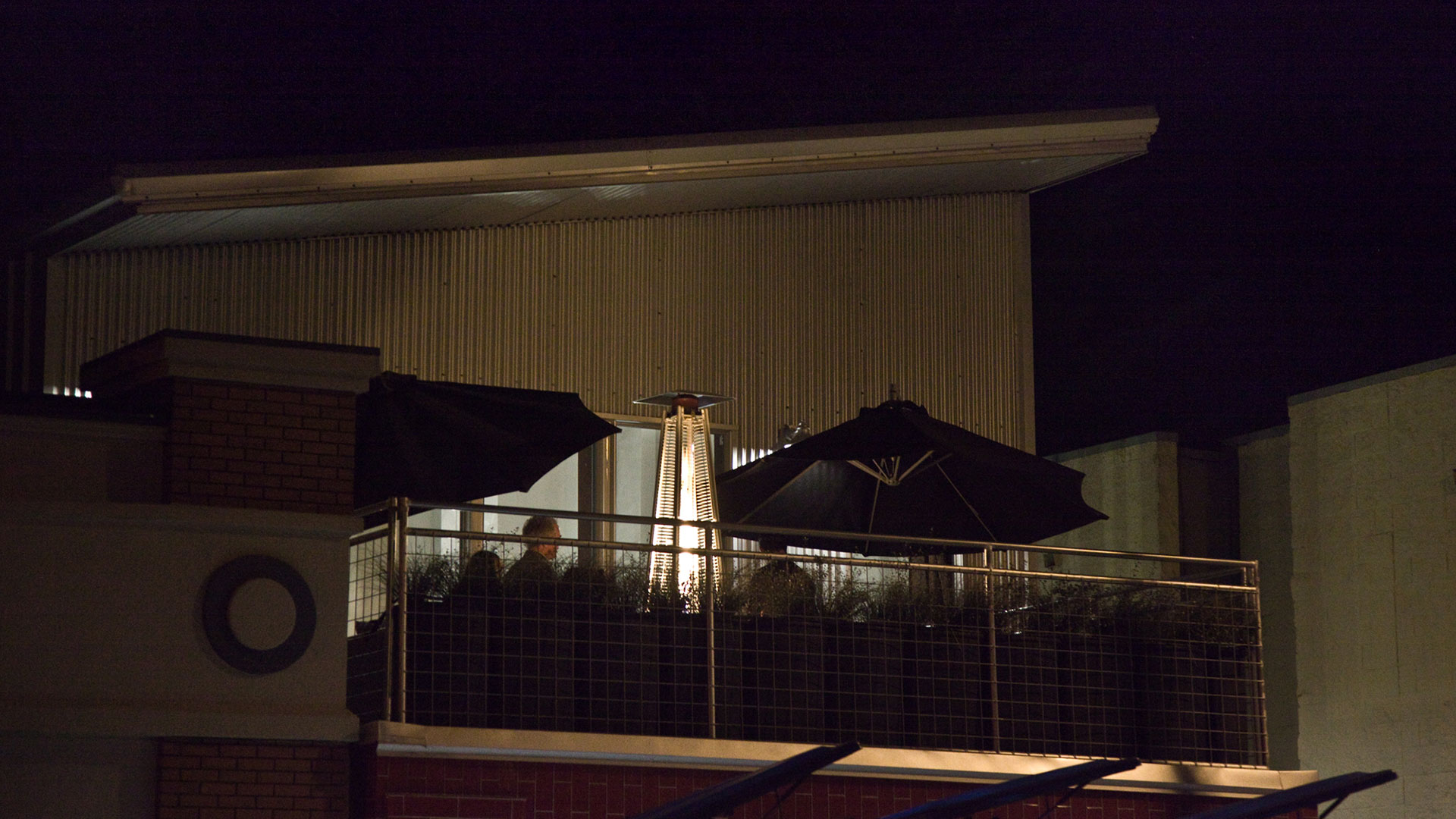 Distant shot of upper, outdoor mezzanine with plants and umbrella