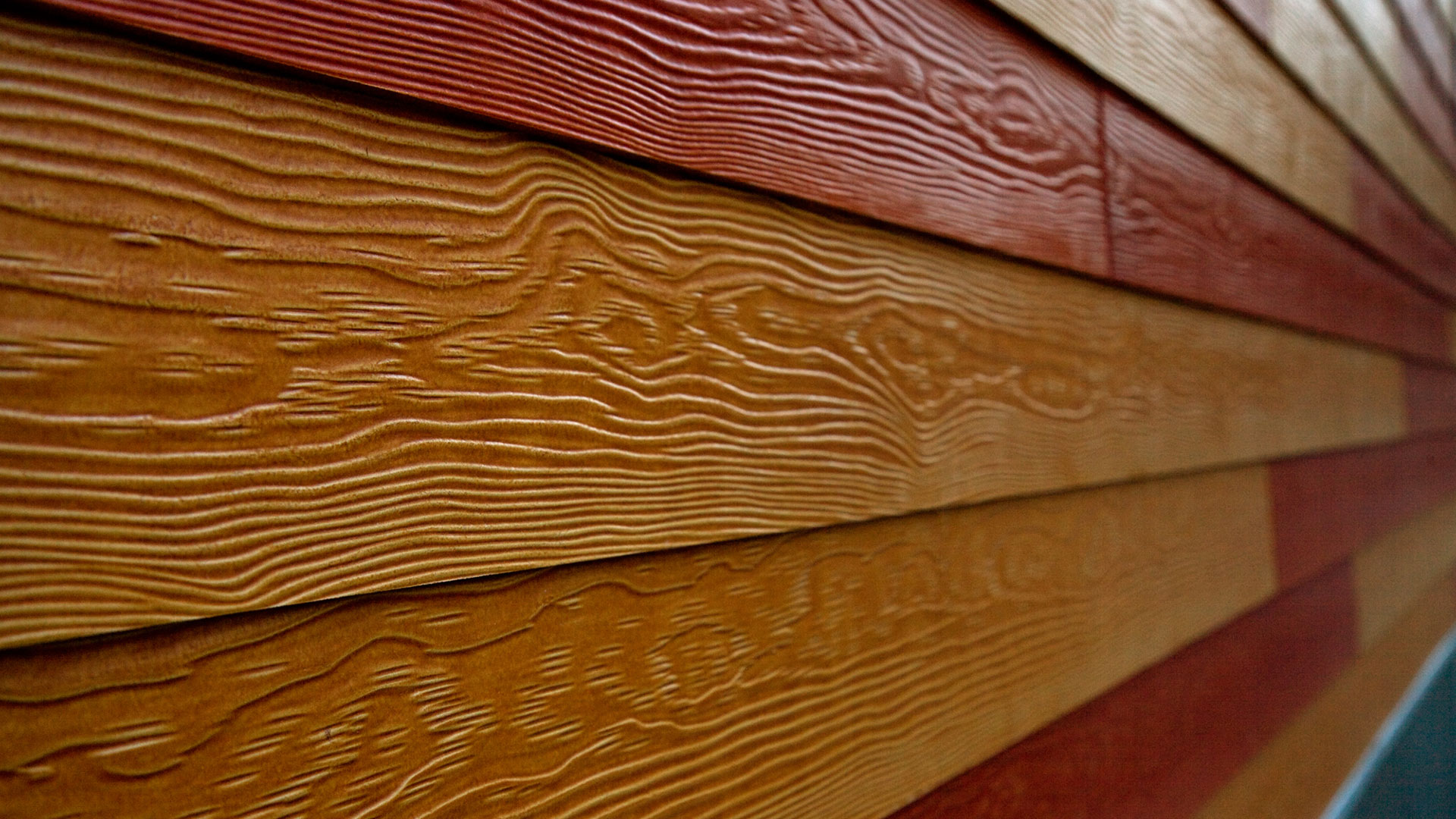 Closeup of wooden exterior paneling of different brown colors, with wooden texture.