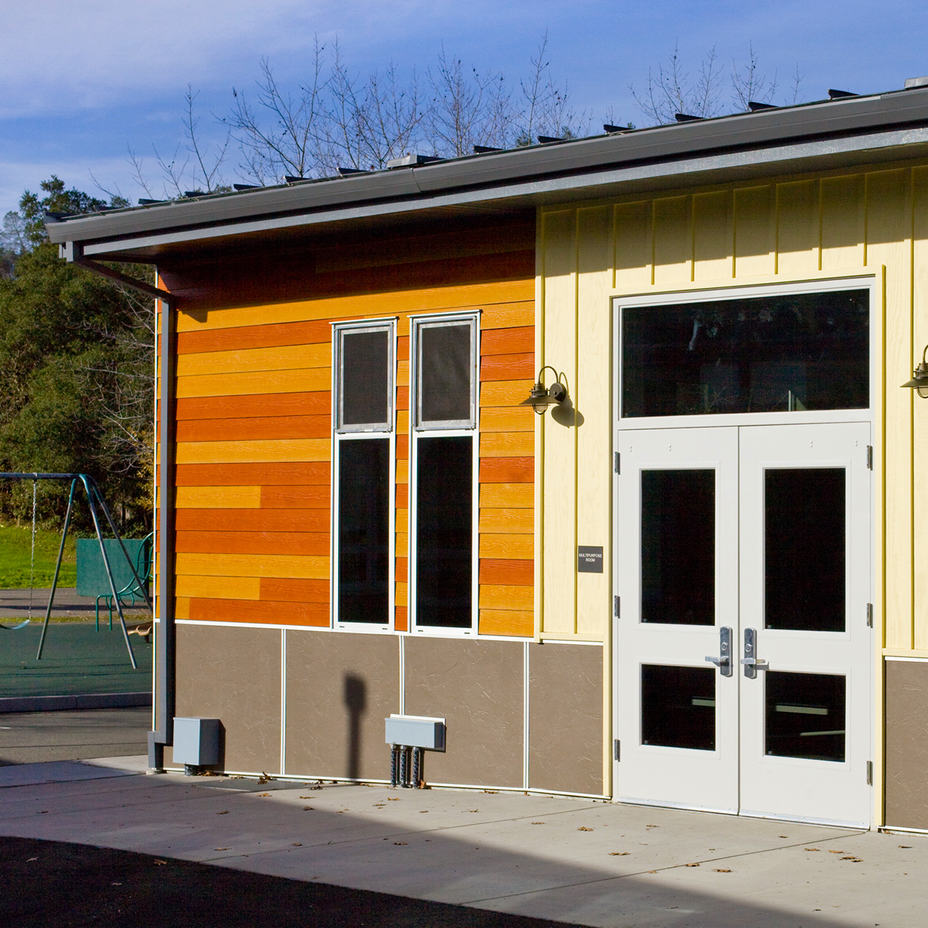 New multi-use room entrance with lighter panels around main doors, and large windows.