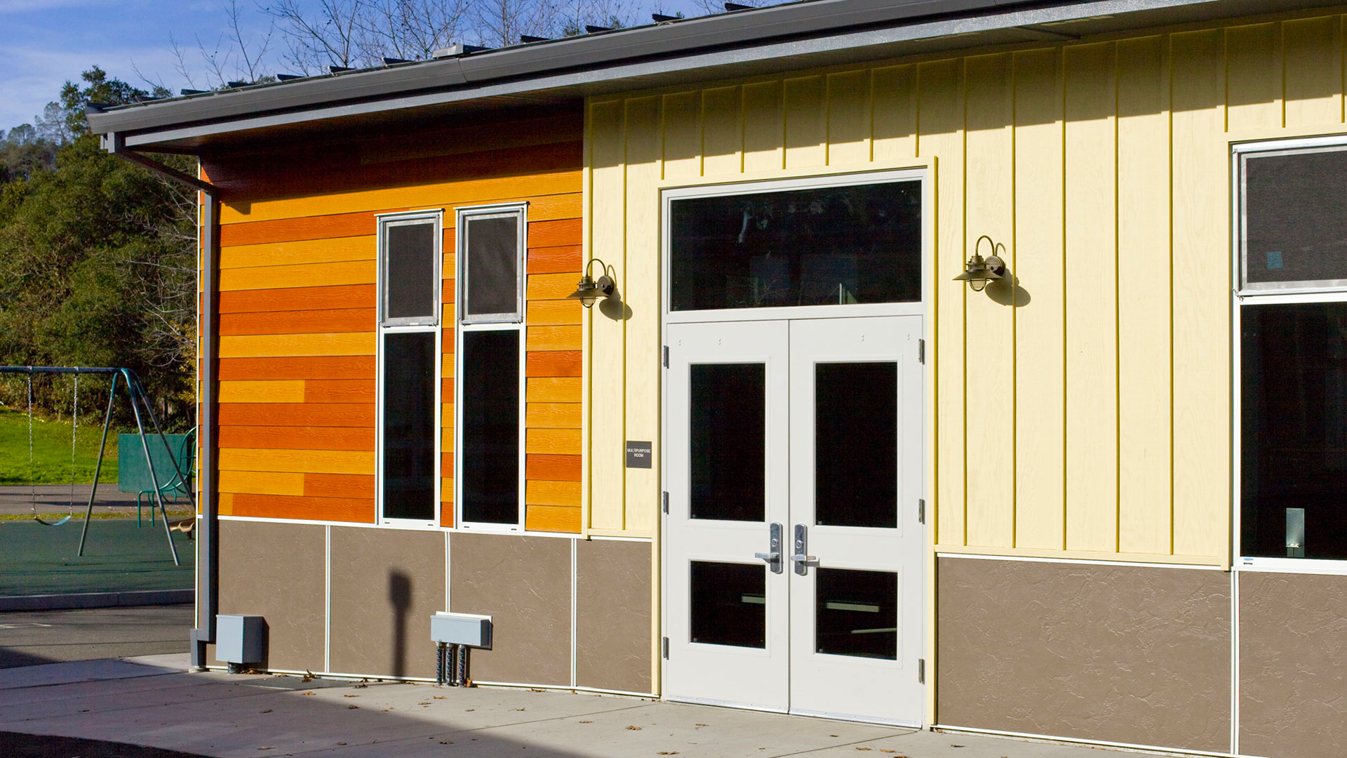 New multi-use room entrance with lighter panels around main doors, and large windows.