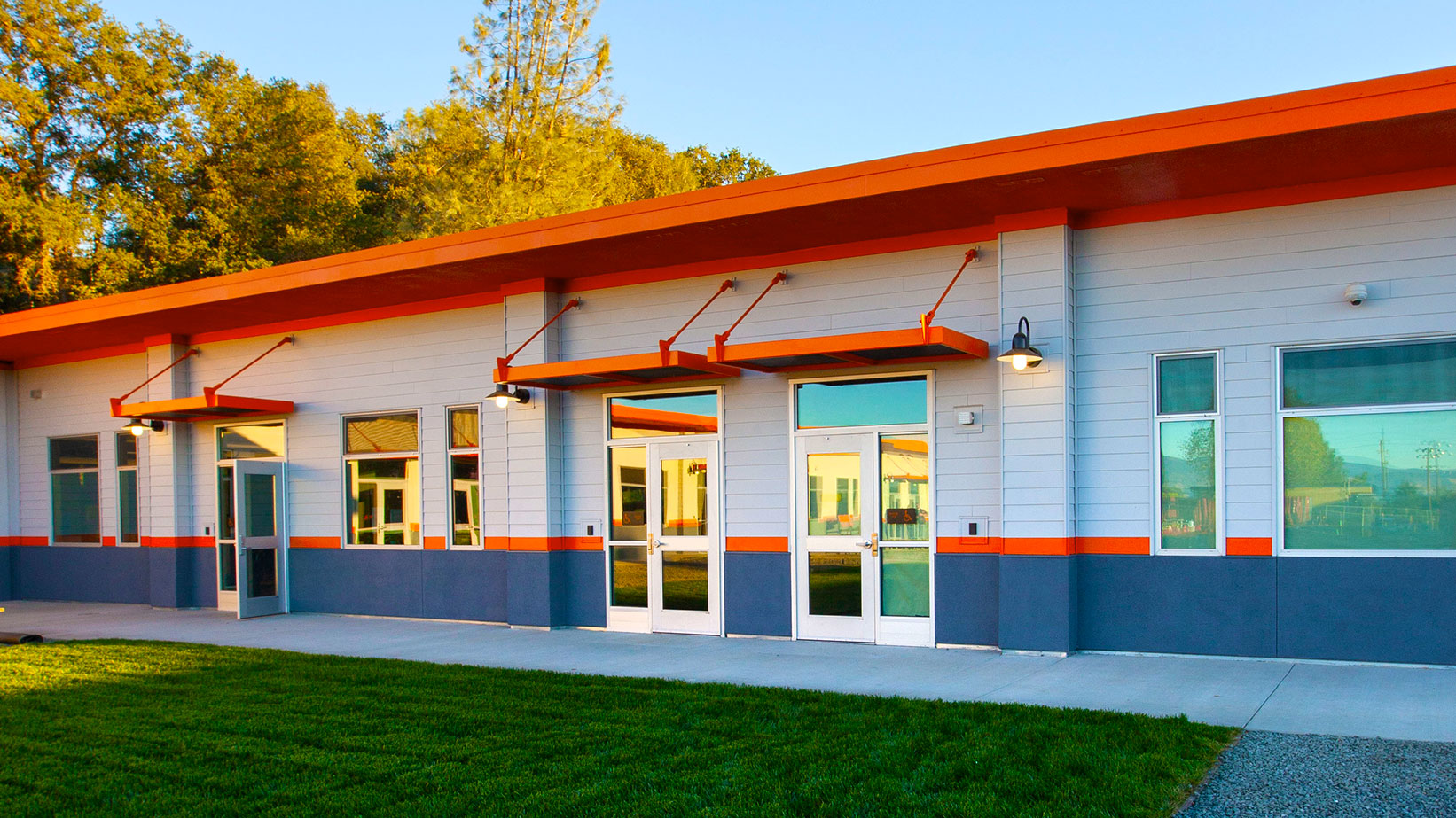 Closeup of two classroom entrances, with orange overhangs over doors, and reflective glass in doors and windows.