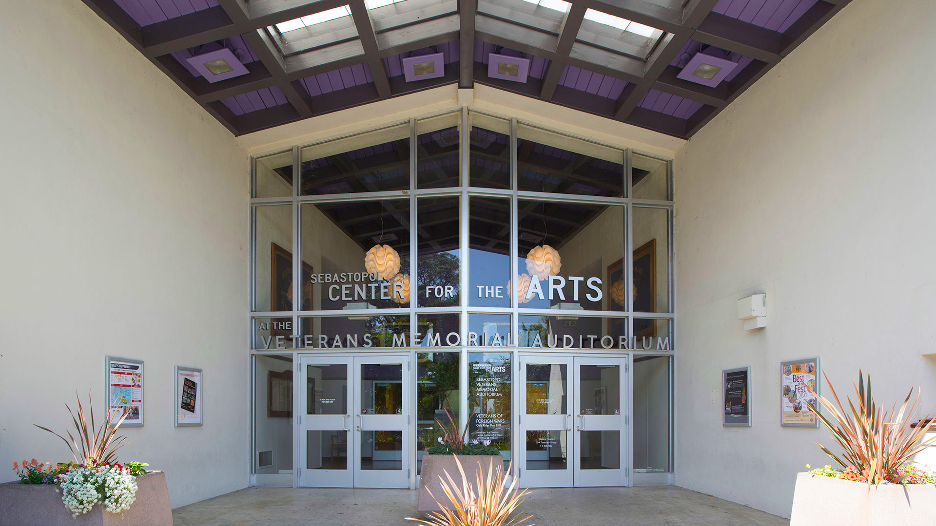 Entrance to the Center for the Arts, with vast glass walls and purple ceiling tiles spaced with skylights