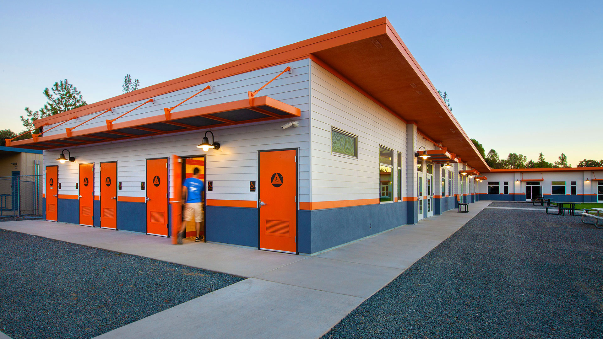 New modular restrooms, with orange doors and awning, on side of classrooms wing.