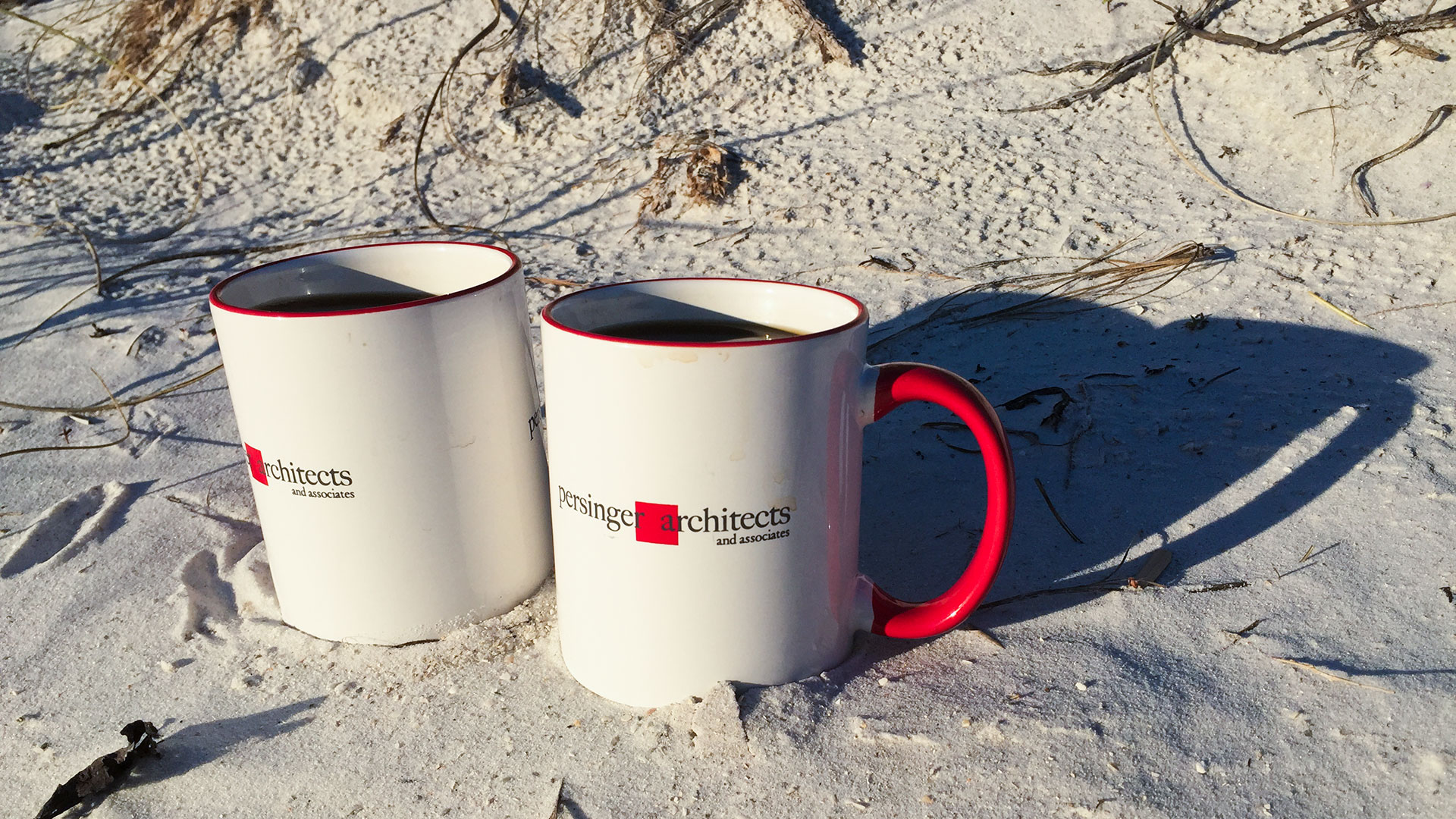 Pair of Persinger mugs sitting on a sandy beach