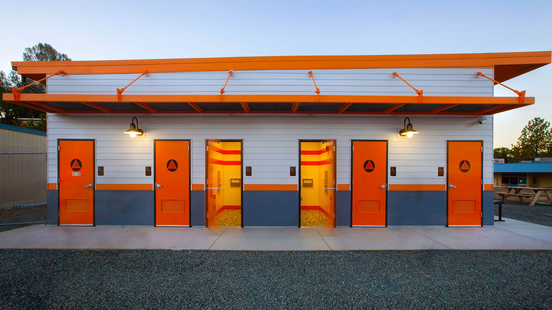 New modular restrooms, with orange doors and awning, on side of classrooms wing.