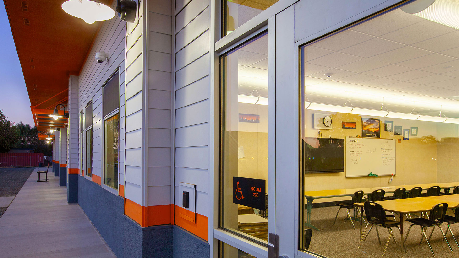 Closeup of modular classroom entrance, with large, clear windows and a black classroom placard.