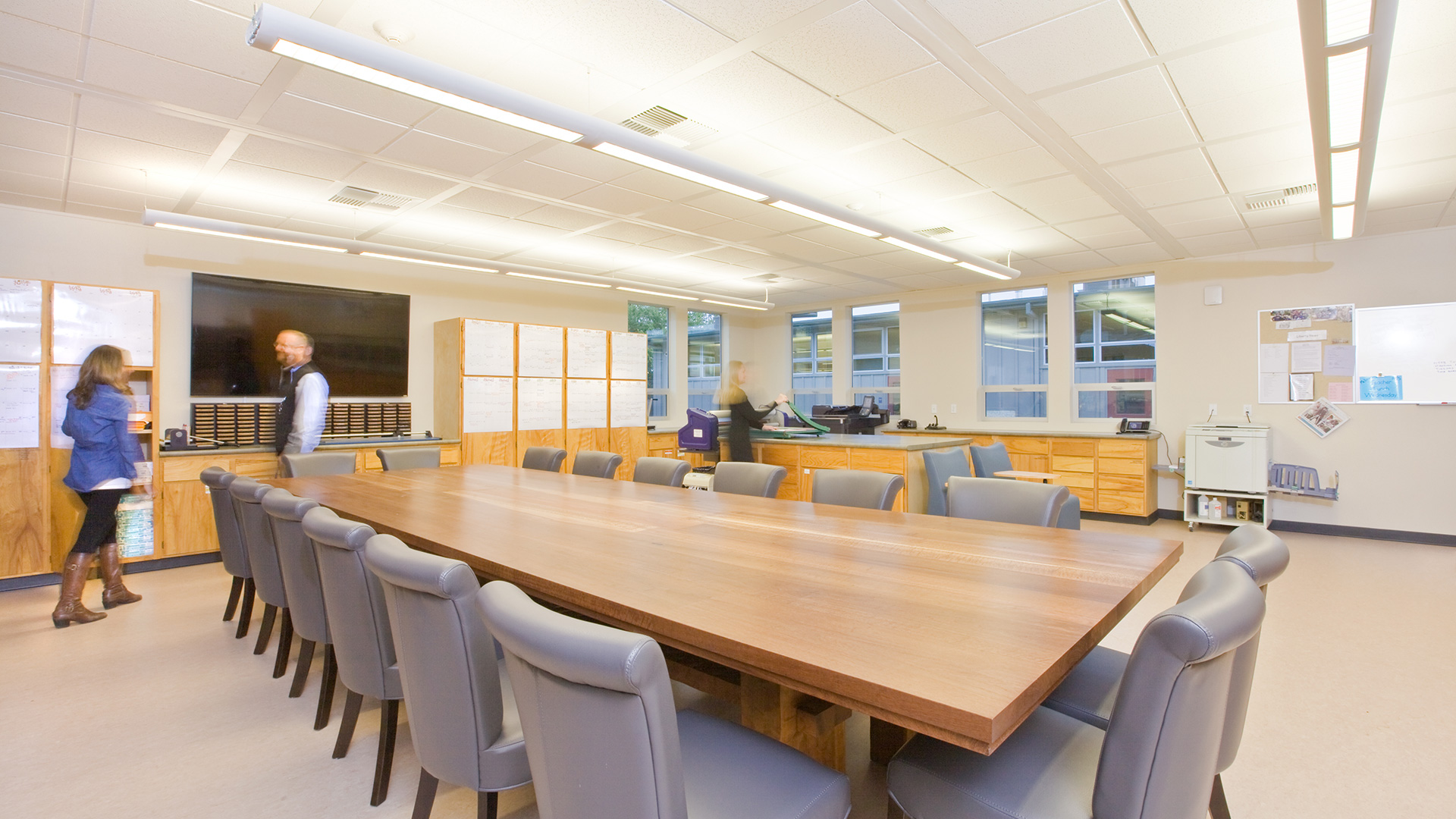 New staff conference room interior, with large wooden table and working area behind.