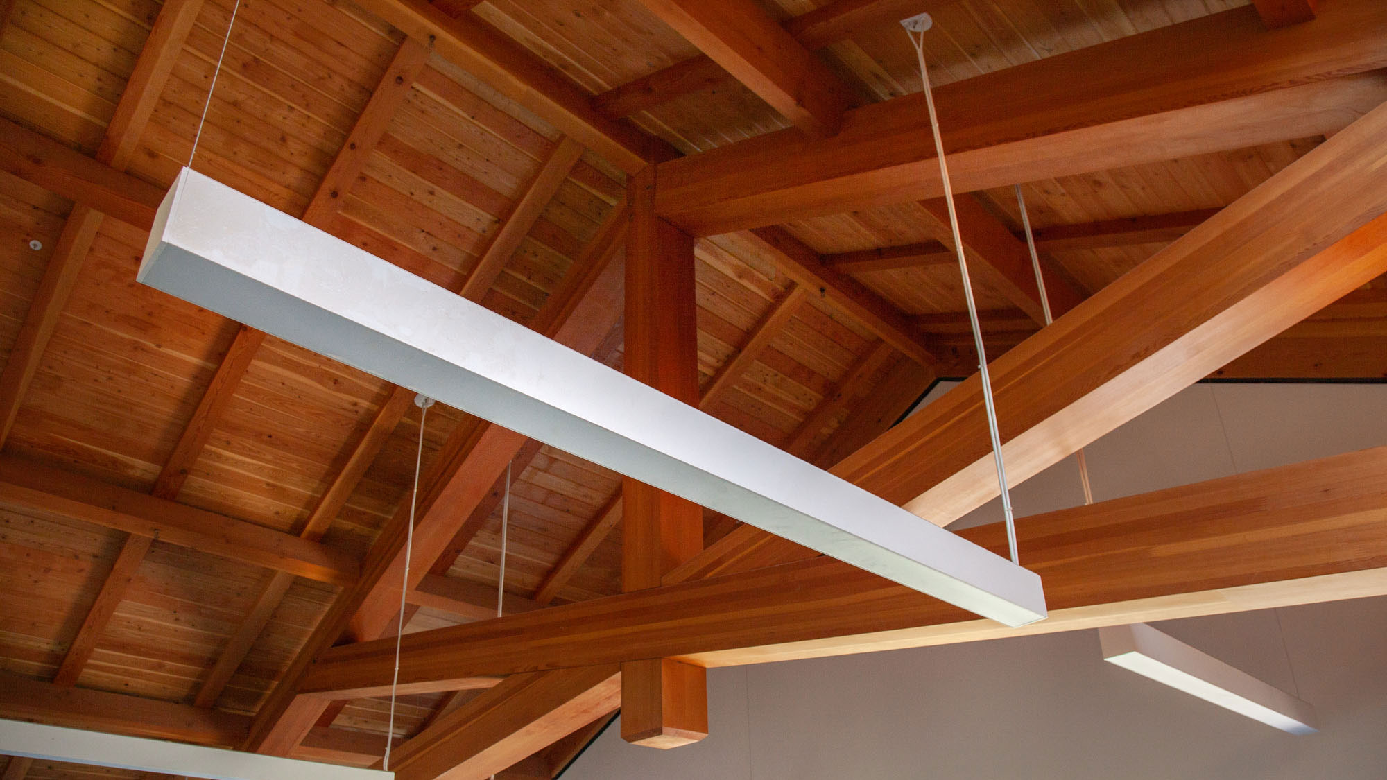 Closeup of geometric wooden truss and hanging light fixture inside the barn.