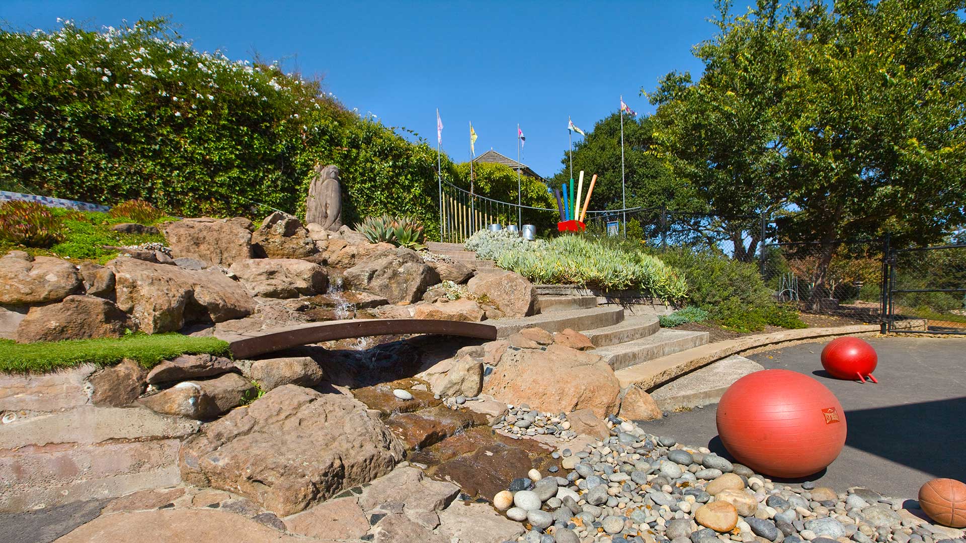 New outdoor area with waterfall area, play toys around, and steps to higher area behind.