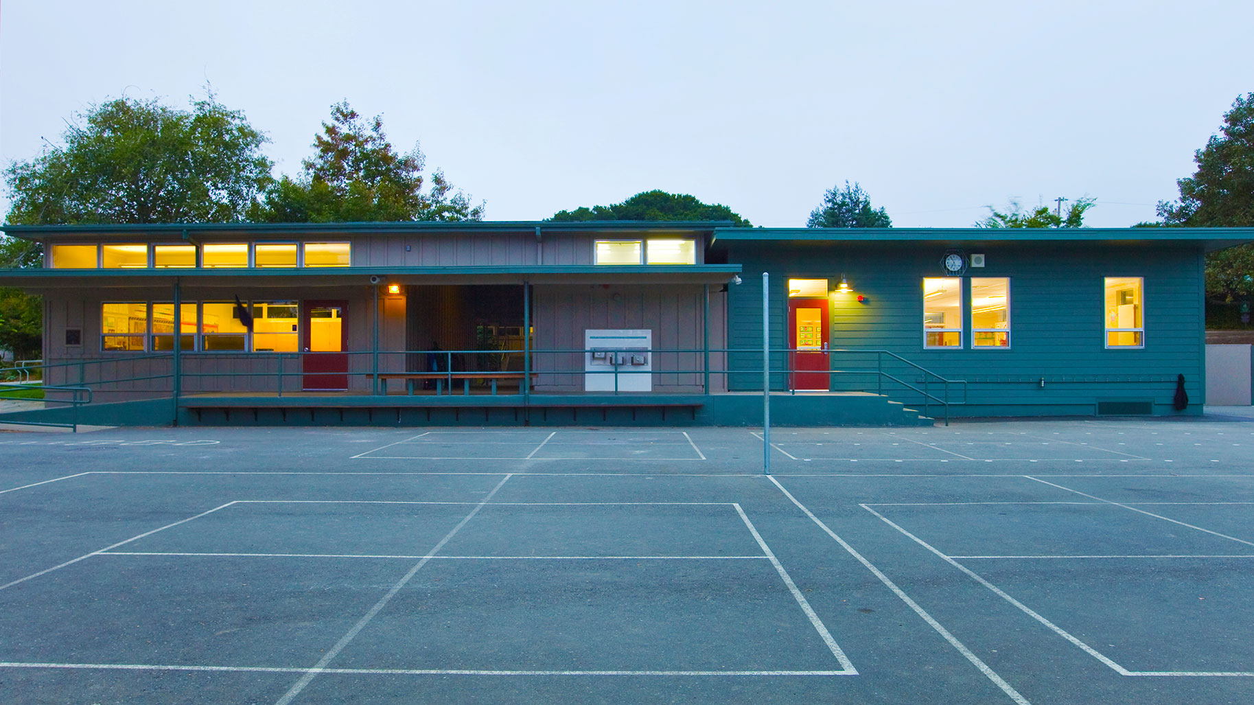 New portable classroom building with blue walls and a orange door, fitting in next to exisitng portable building.