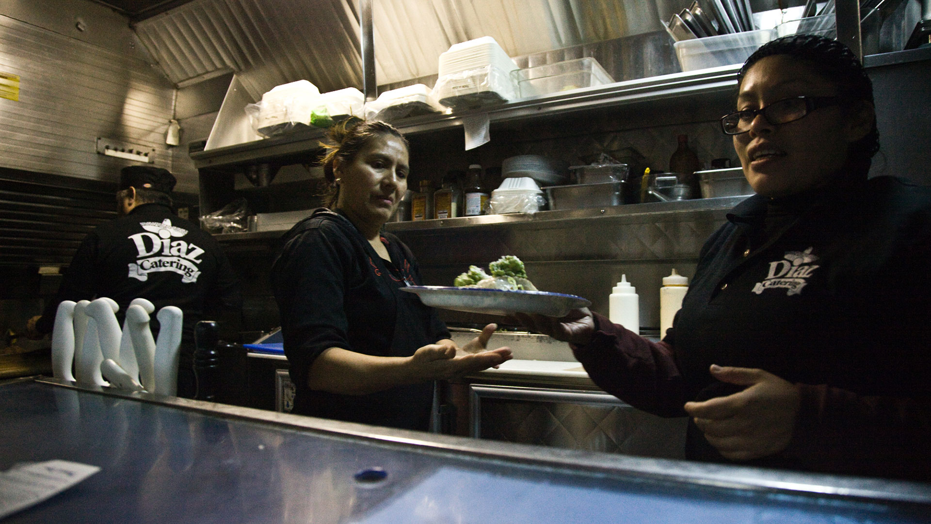 Looking into food truck, working preparing food inside