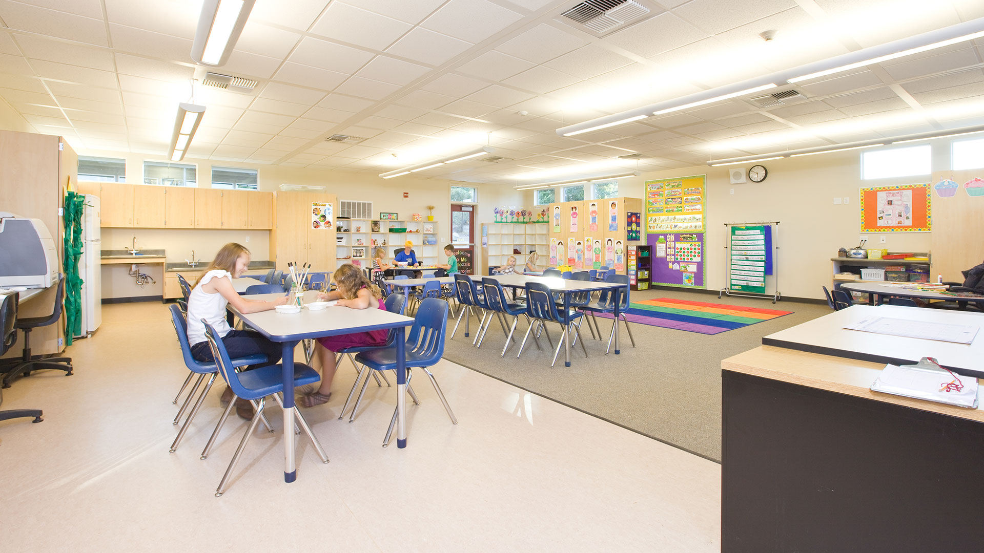 New classroom interior, with carpet and vinyl flooring for desk and seating areas.