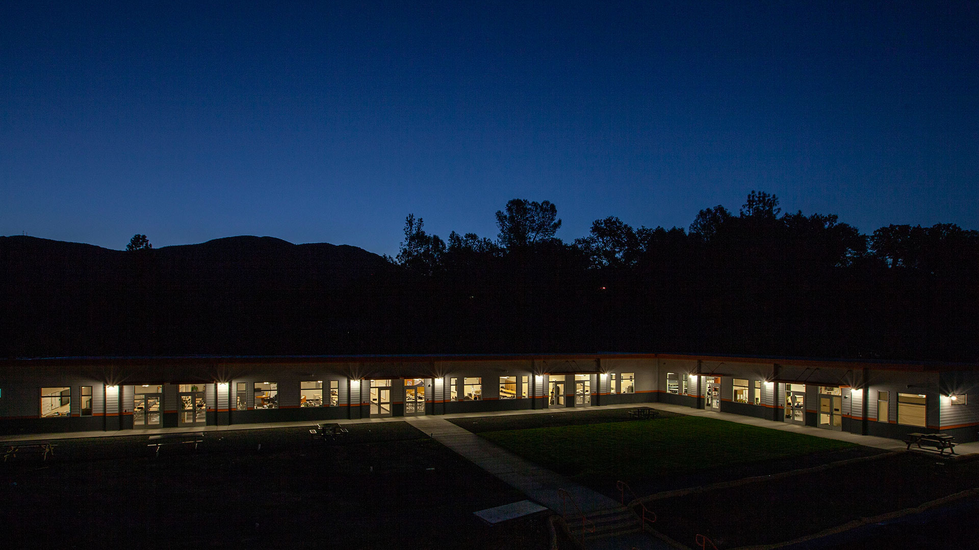 Modular classroom wing at night, with classroom windows illuminated.