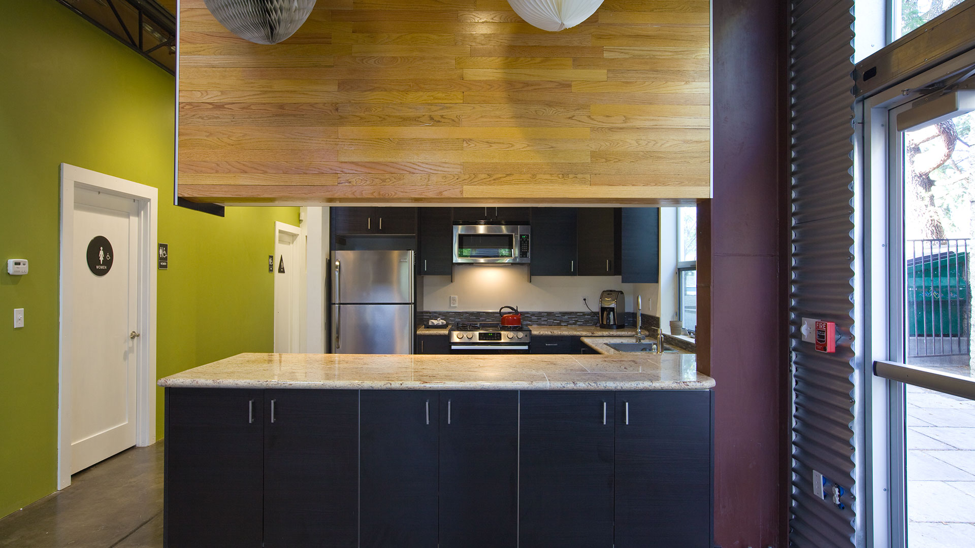 Office kitchen with black cabinets and chrome appliances and granite countertops