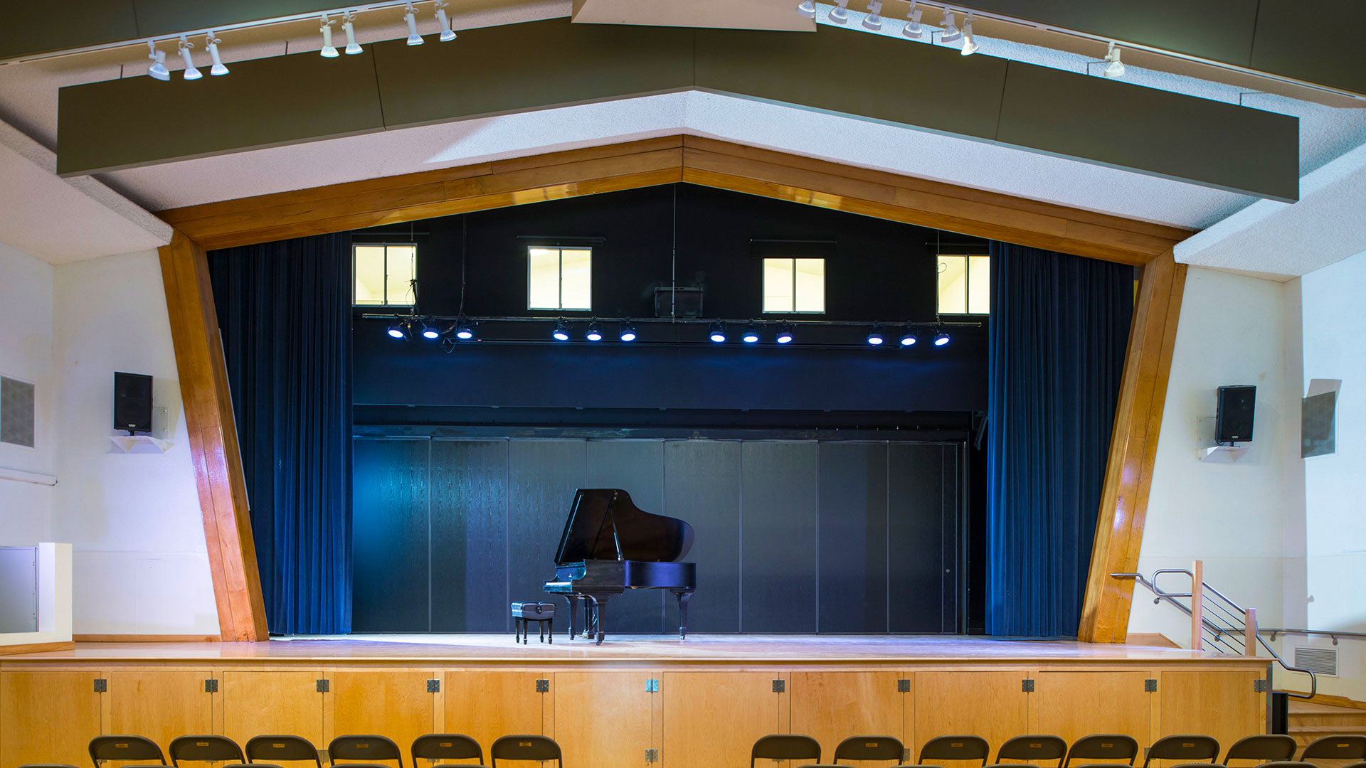 Performance stage at the Center for the Arts with blue background and curtains. Grand piano on stage.