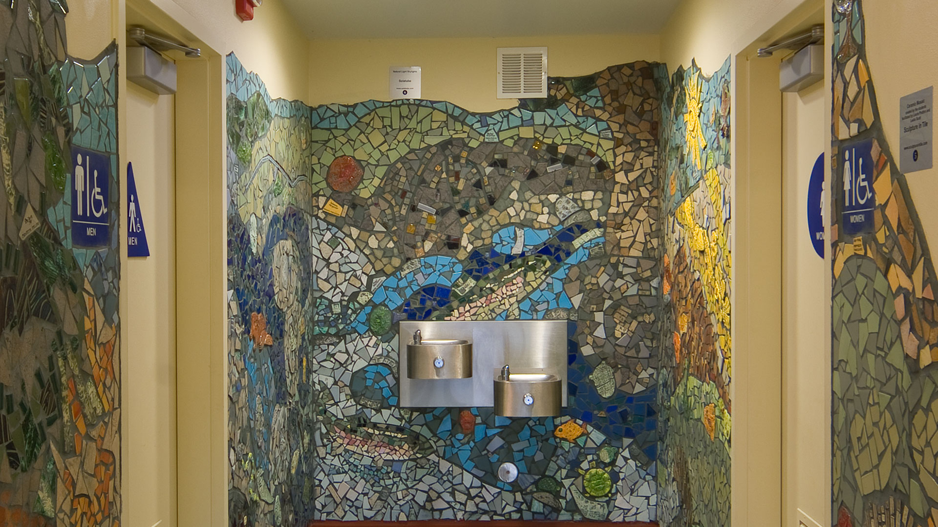 Interior drinking fountain surrounded by a flowing mosaic resembling water.