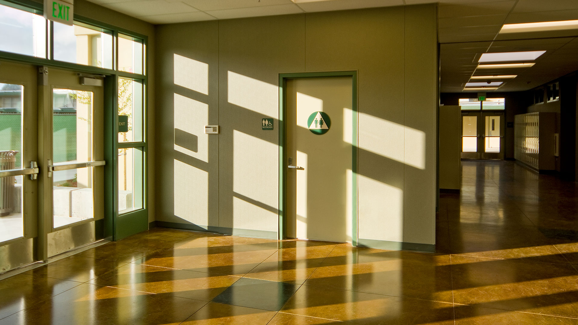 Interior of classroom wing with light shining in through entrance and illuminating floor and walls.
