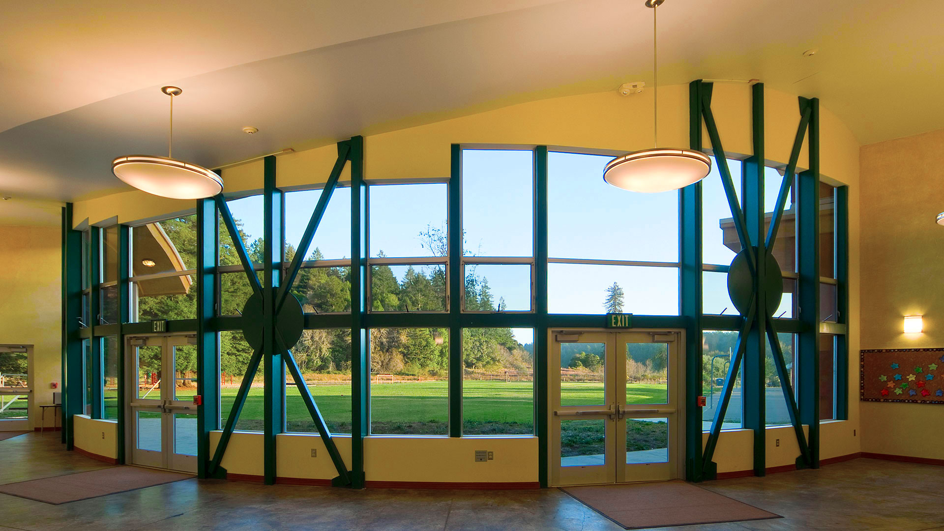 Interior hallway behind curved wall with large windows. Yellow walls contrast to the green trim.