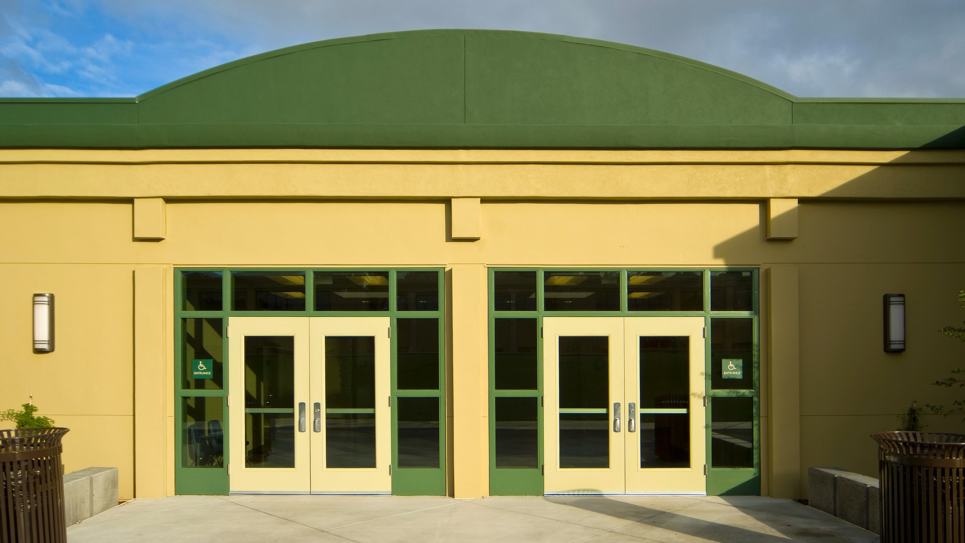 One story modular classroom wing with beige walls and green details, and two large double door entrance.