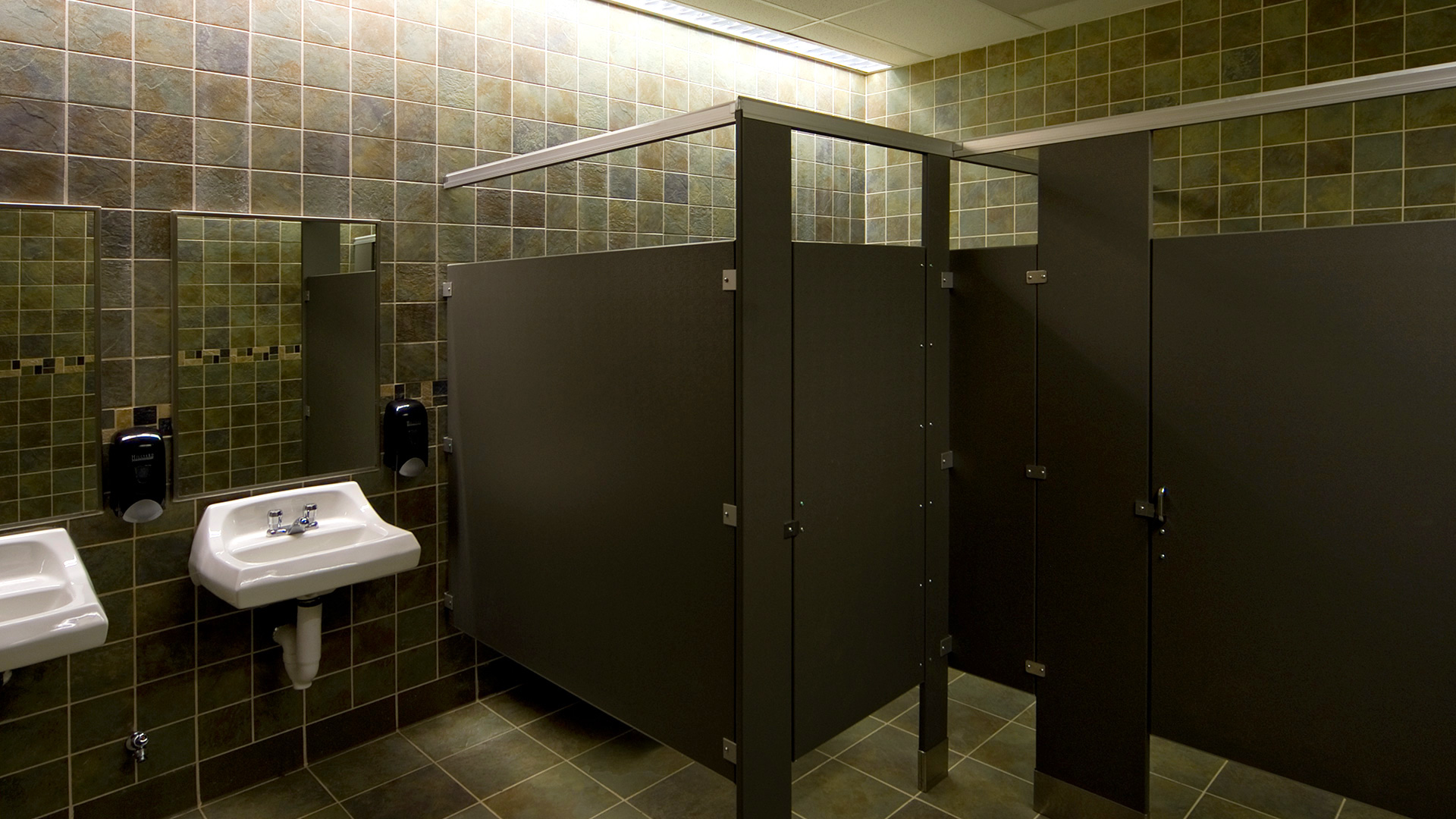Restroom interior, with black divider walls and gray tile walls and floor.