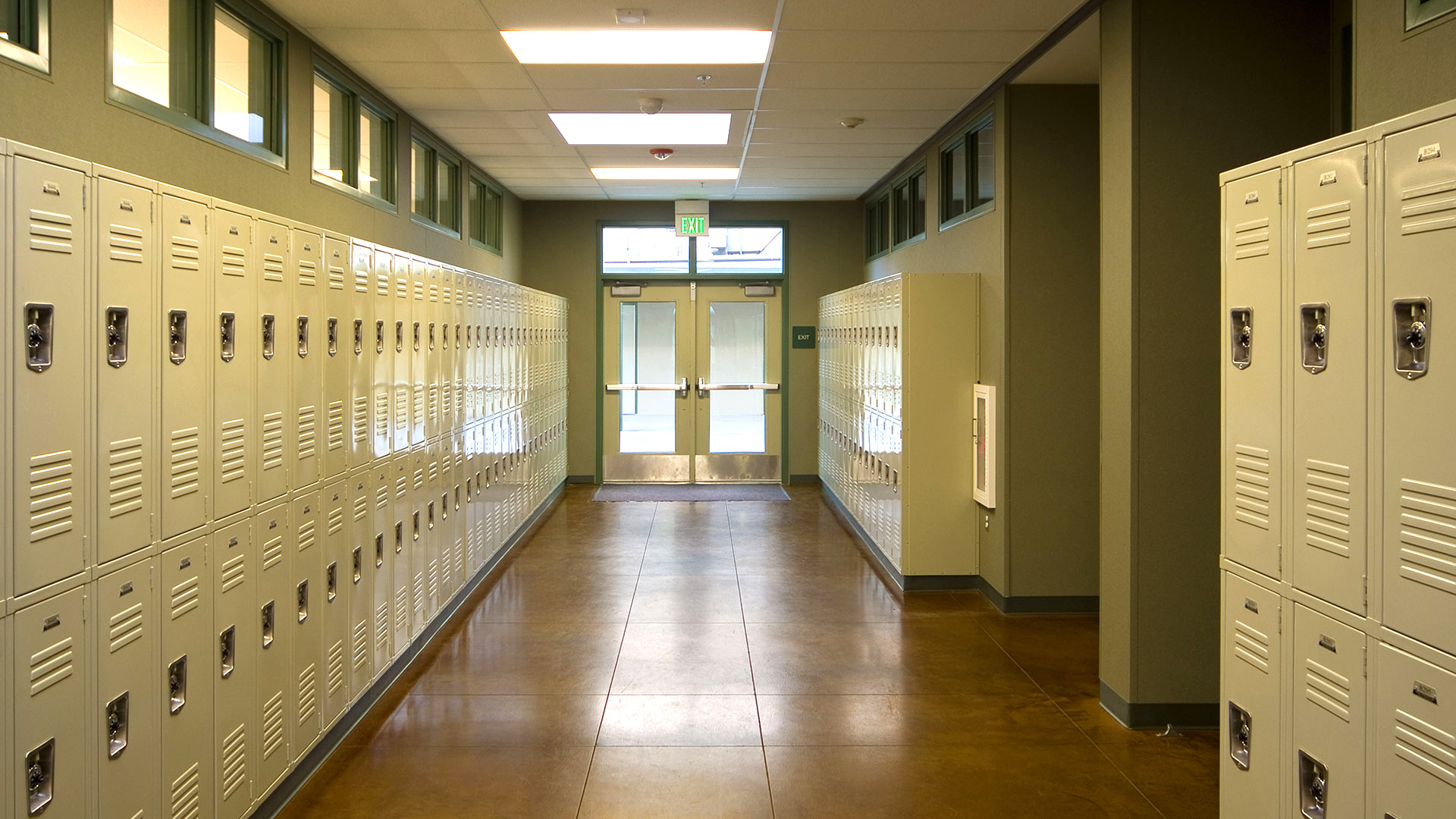 Hallway interior, with lockers flanking left and right. Brown floors below light green walls and ceilings.