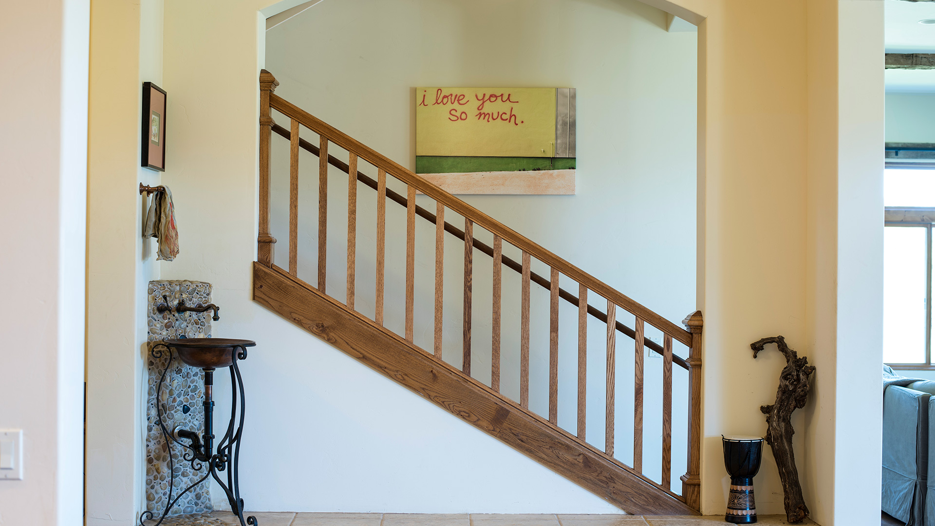 Stairs adjacent to foyer behind a curved archway. Handwashing sink and decorative driftwood flank archway.