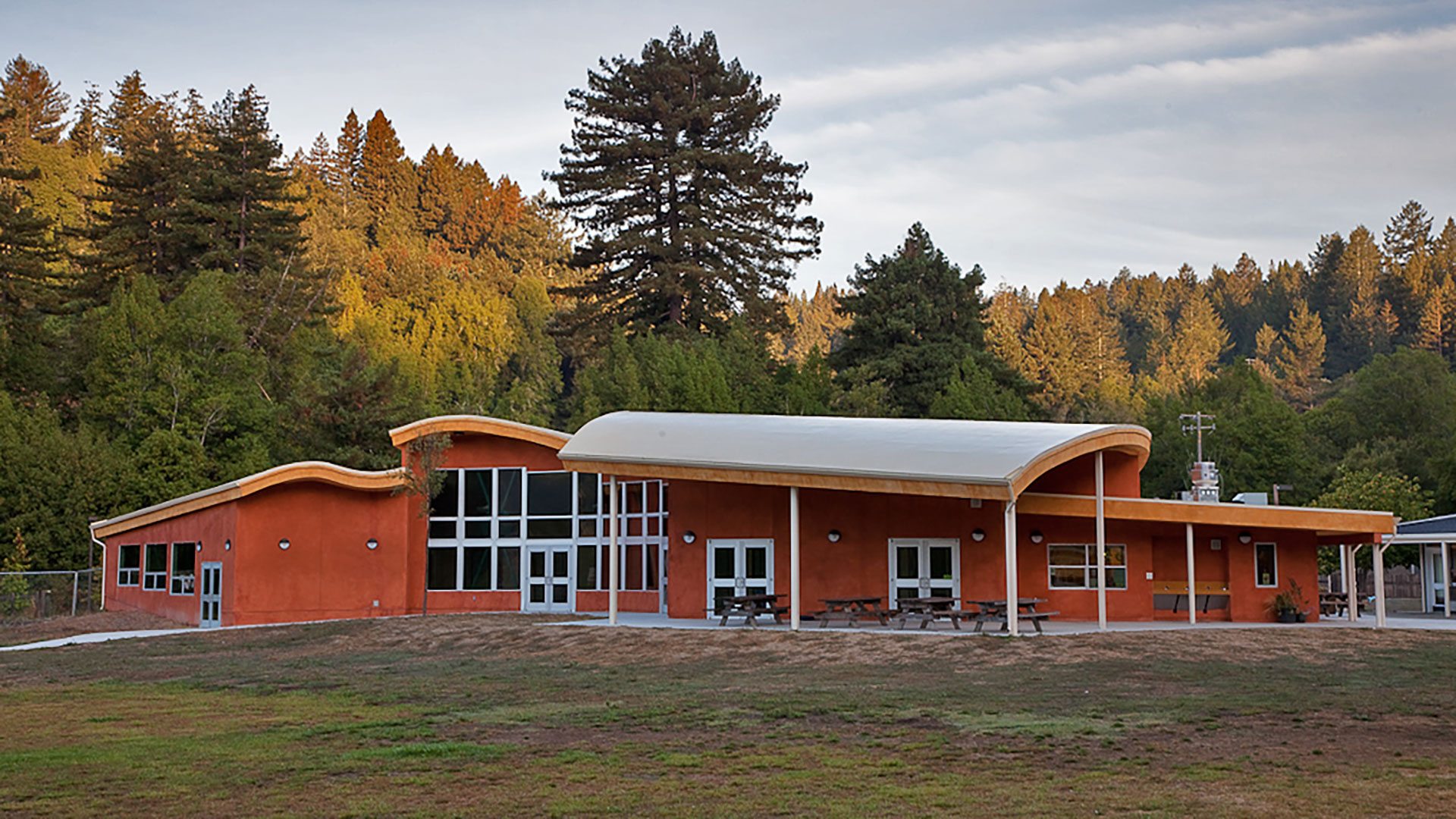 School with orange walls and vast curved roof sitting above double doors.
