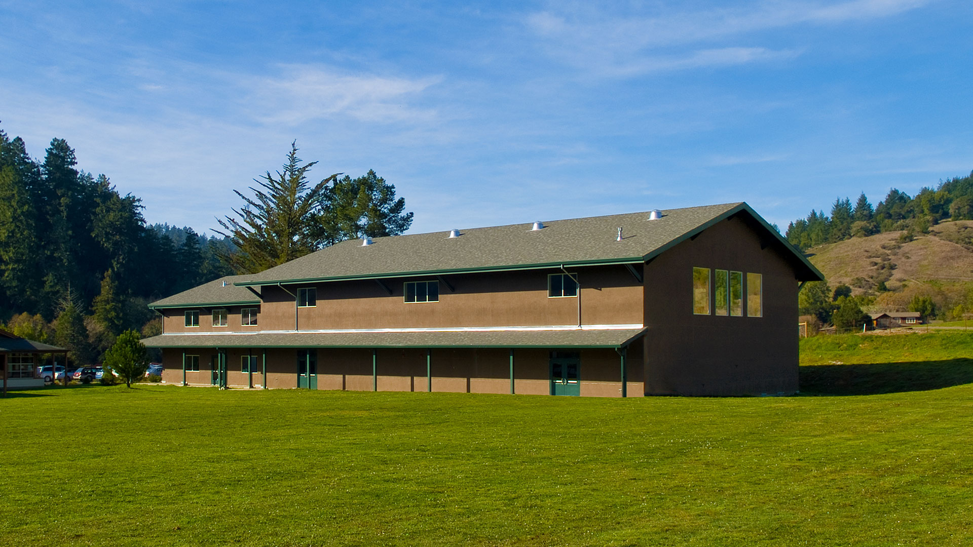 Gym building exterior with brown walls and green trim, barn-like design fits in with rural setting.