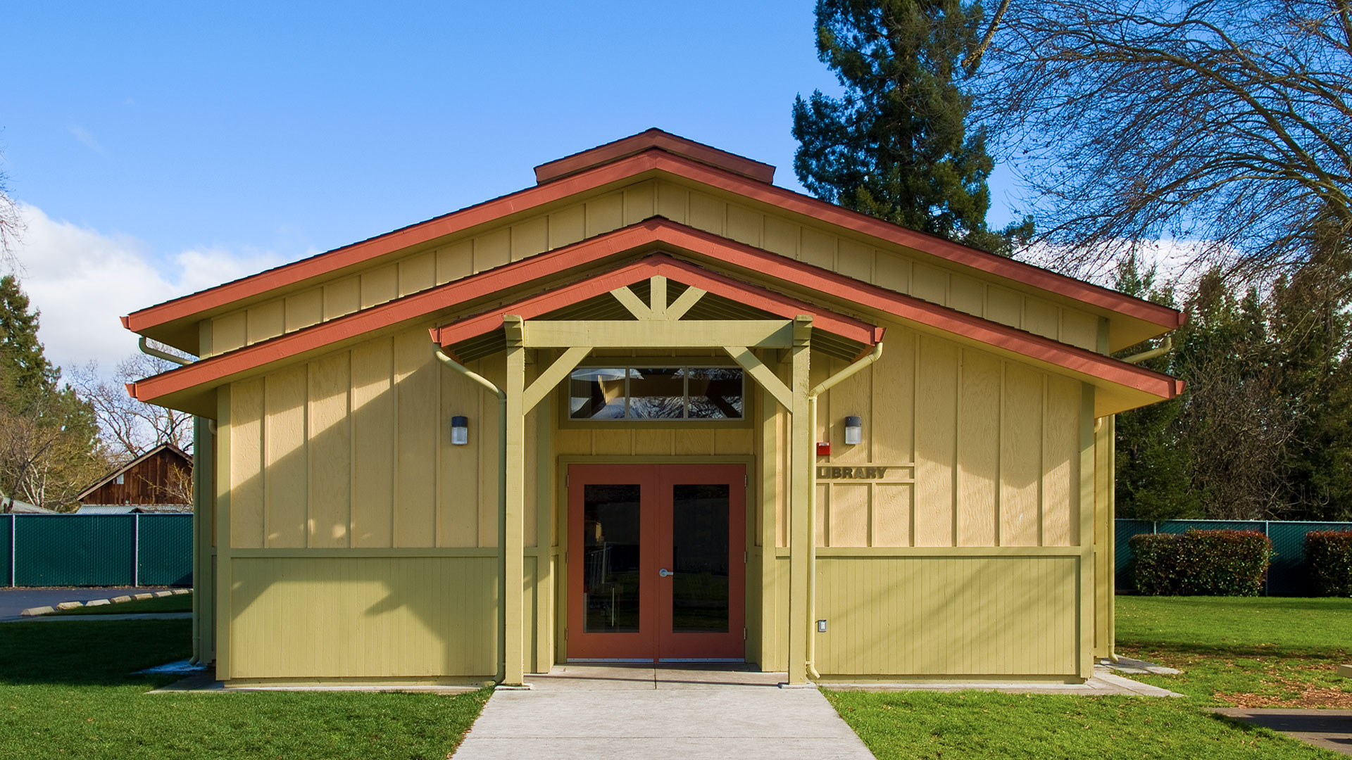 Library building entrance with yellow walls and light green wainscot, and orange doors.
