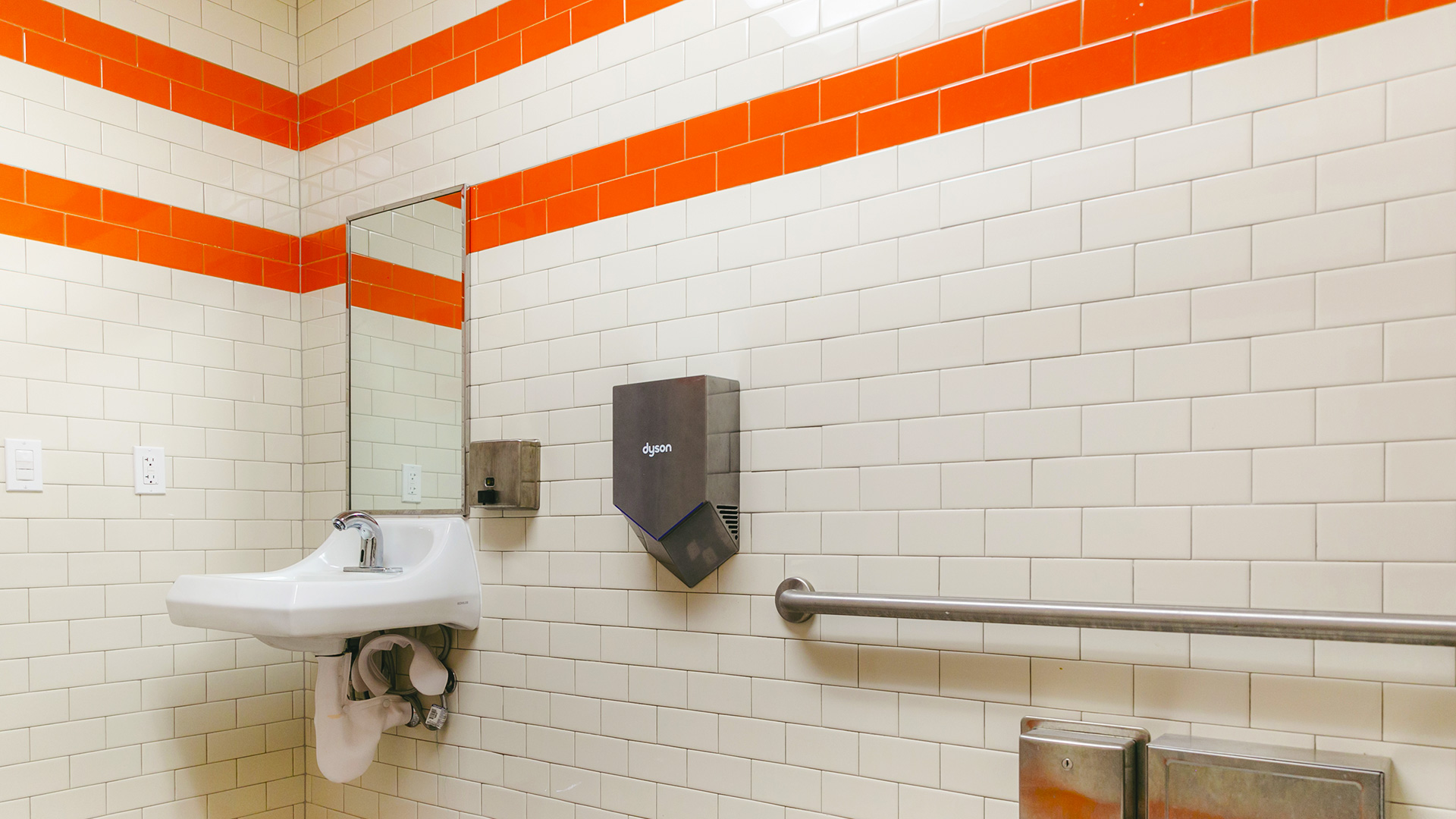 Portable restroom interior, with white and orange tiles.