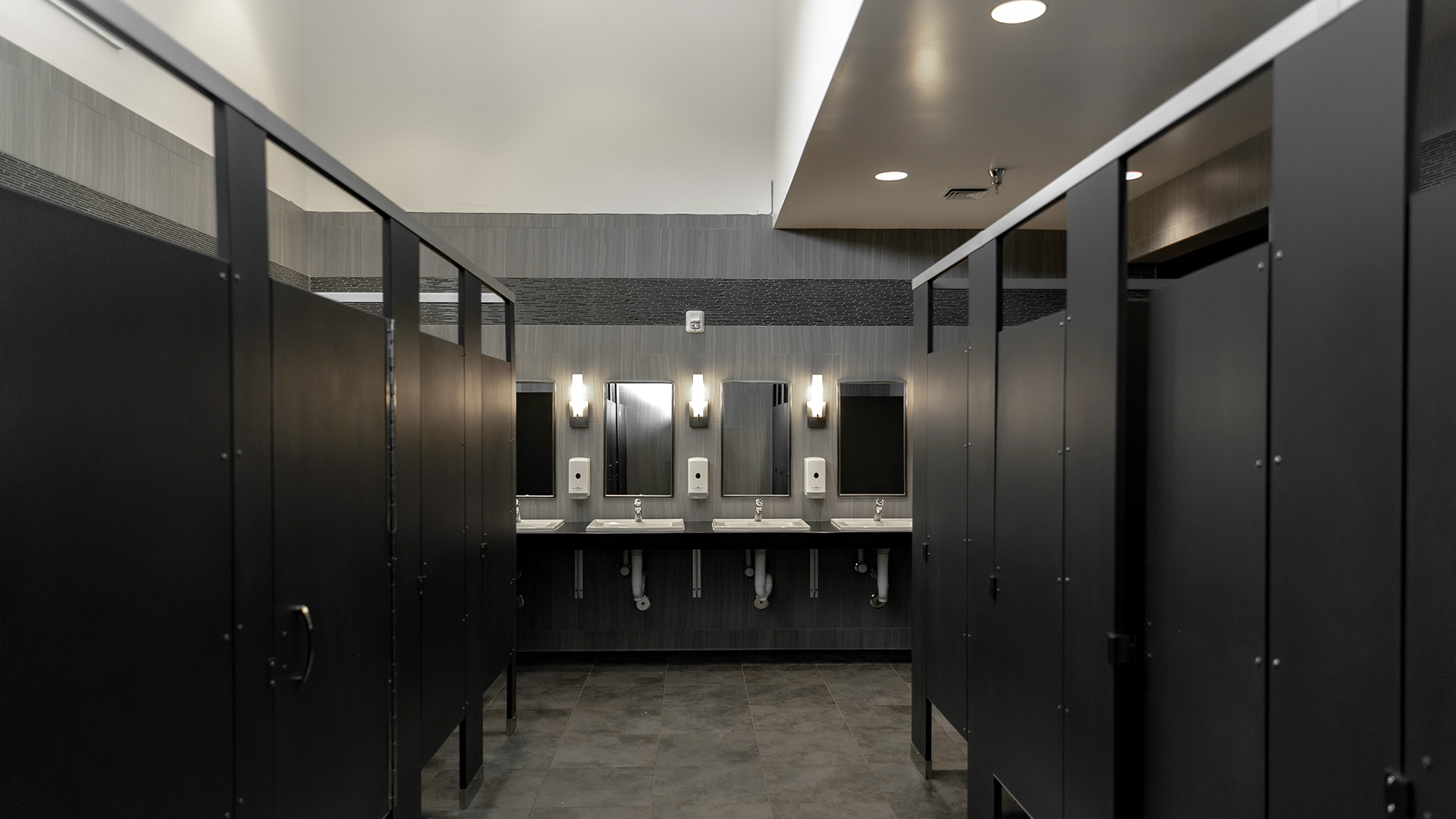 Interior of bathroom, with double height ceilings, gray colors and black trim.
