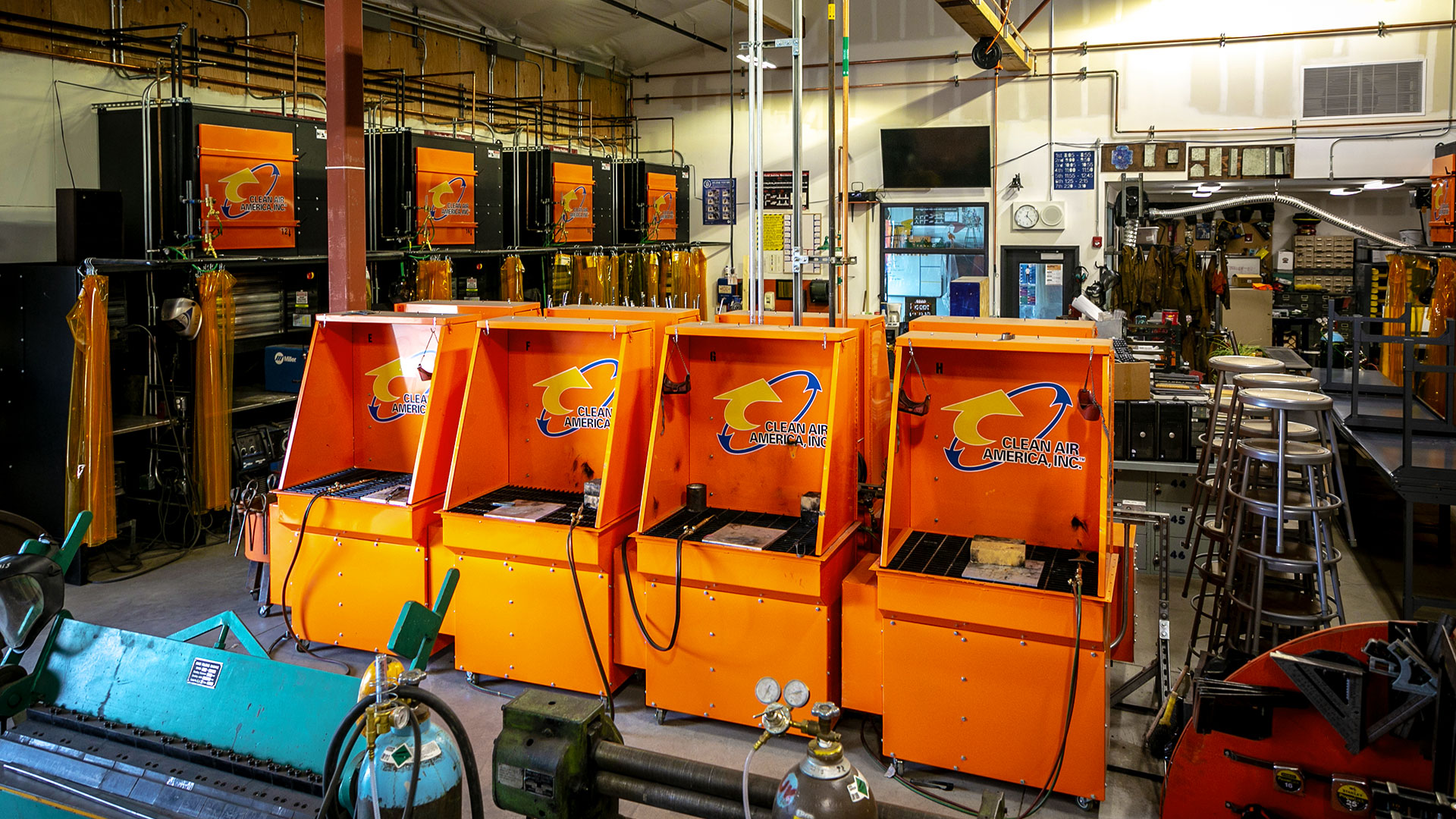 Shop interior with welding booths in foreground and in background, pipes running to all booths.