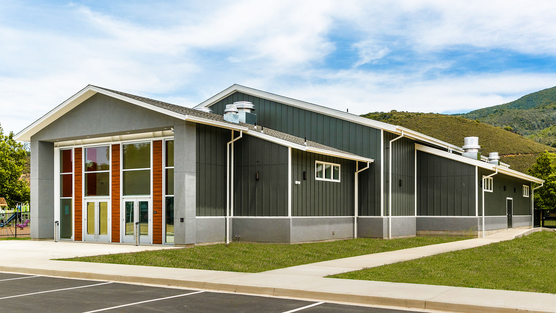 Exterior of Multi-Use Room. Gray walls with white trim and light wainscot, make up the multi-sectioned building.