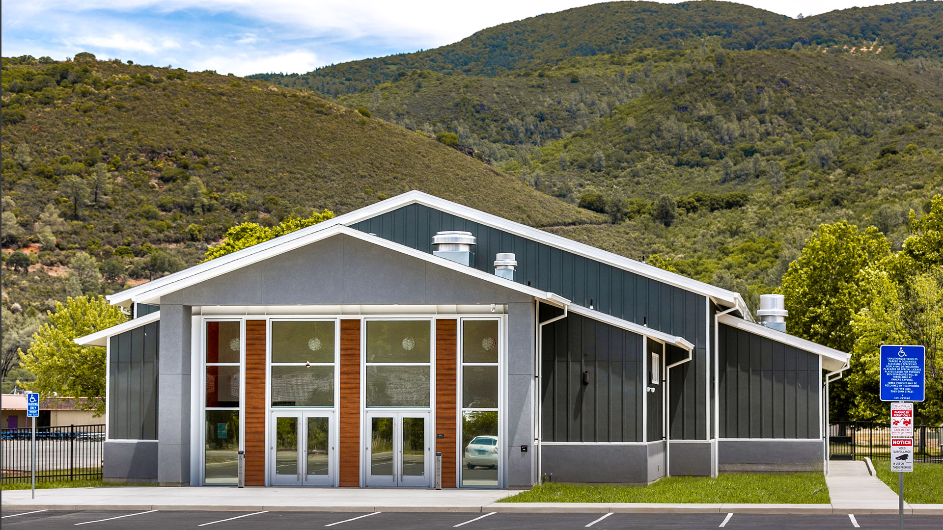 Exterior of Multi-Use Room. Gray walls with white trim and light wainscot, against the mountains rolling behind.