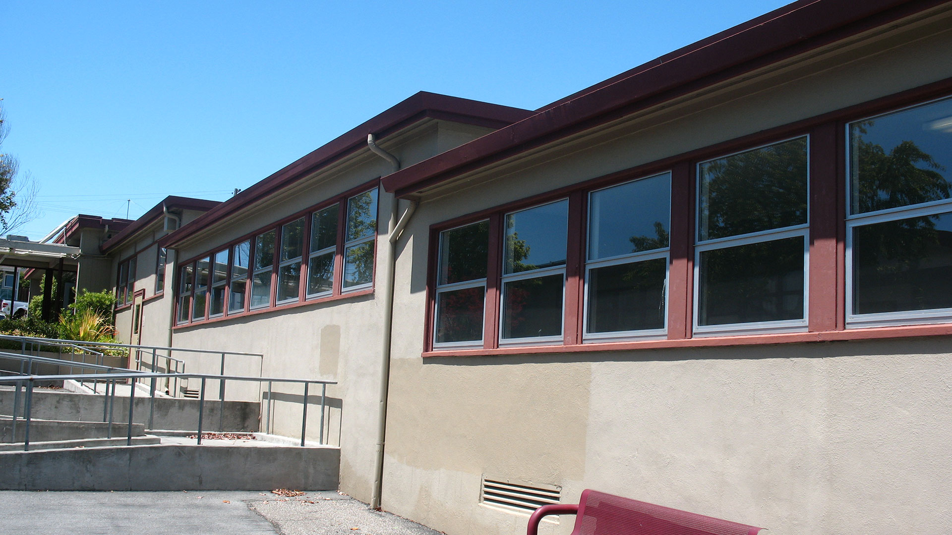 Classroom exterior wtih beige walls and windows with red trim.