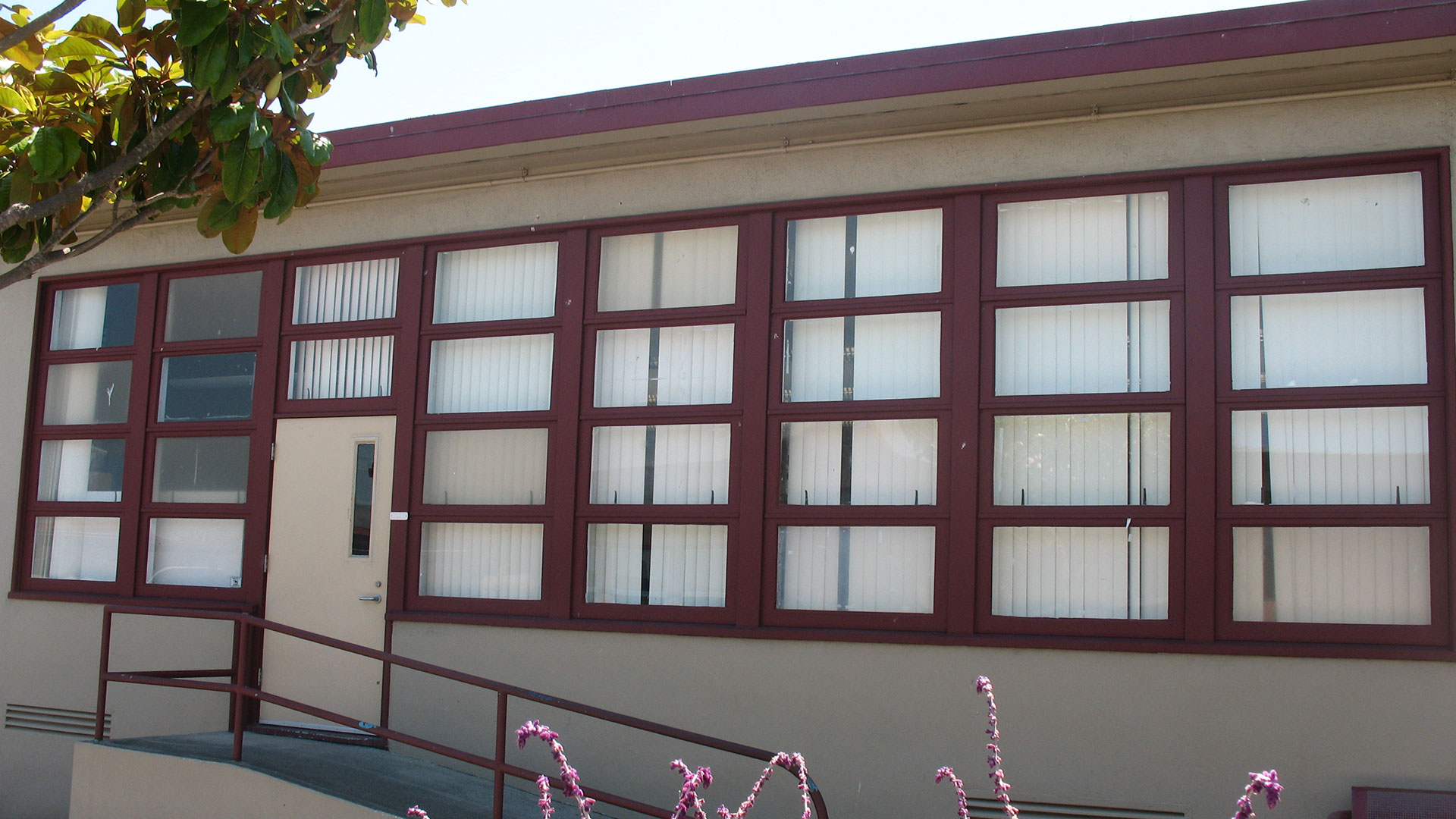 Classroom exterior wtih beige walls and windows with red trim.