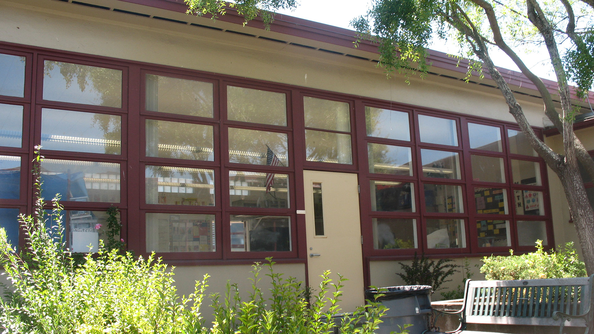 Classroom exterior wtih beige walls and windows with red trim.