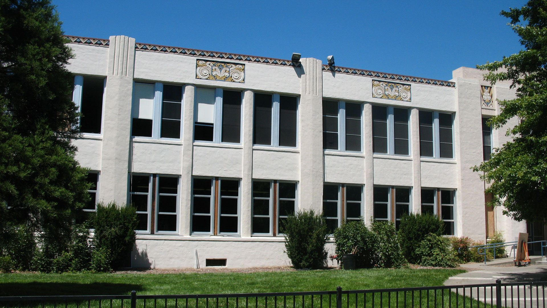 Concrete school building with two stories of large windows, with some windows blocked out.