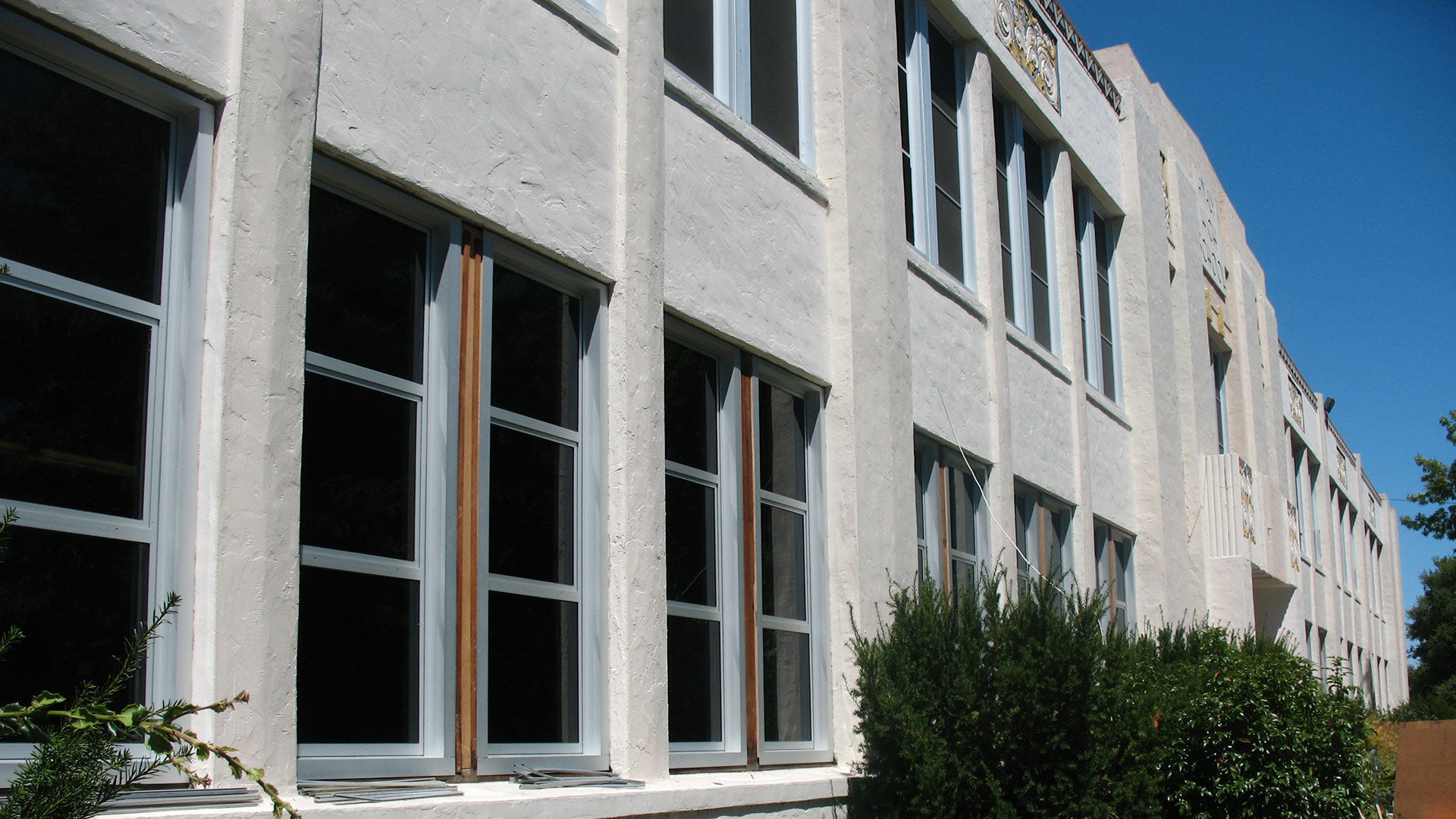 Concrete school building with two stories of large windows, with some windows blocked out.