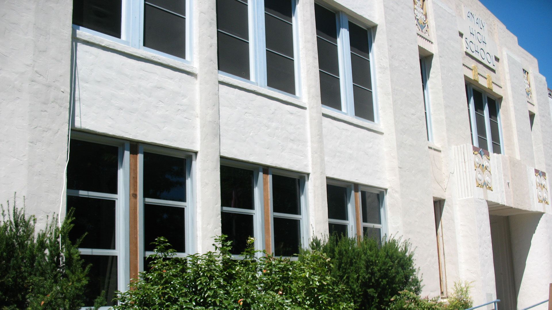 Concrete school building with two stories of large windows, with some windows blocked out.