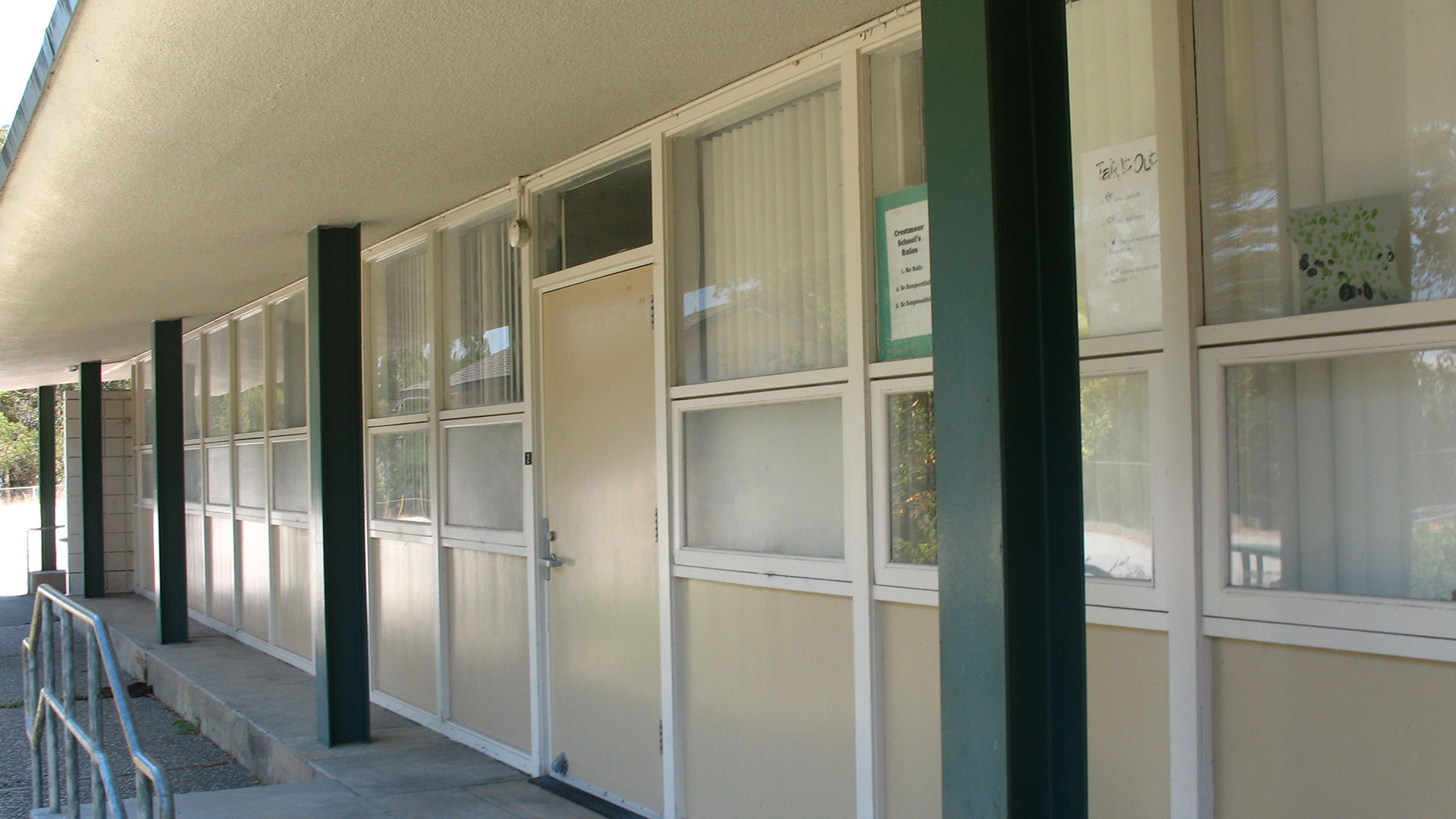 School building with beige walls and green trim, and windows.