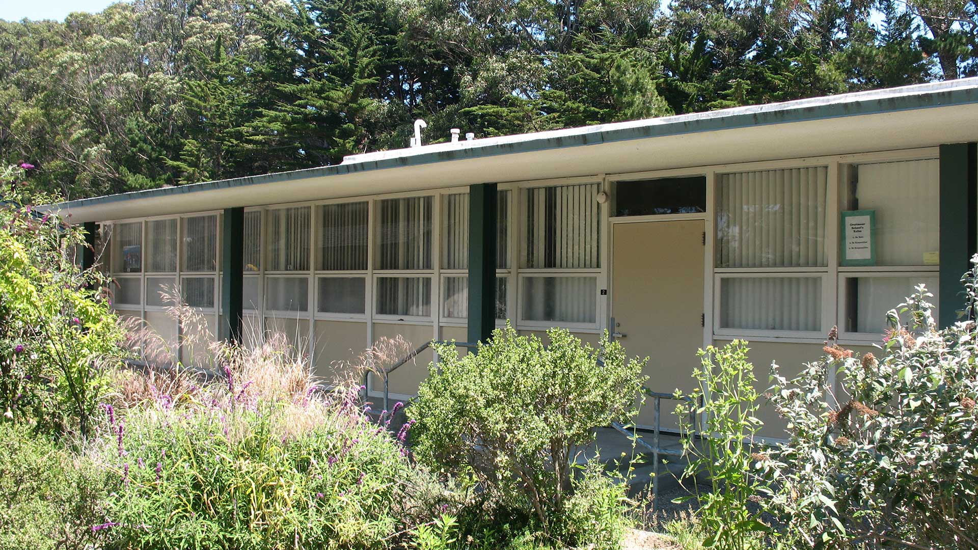 School building with beige walls and green trim, and many windows.