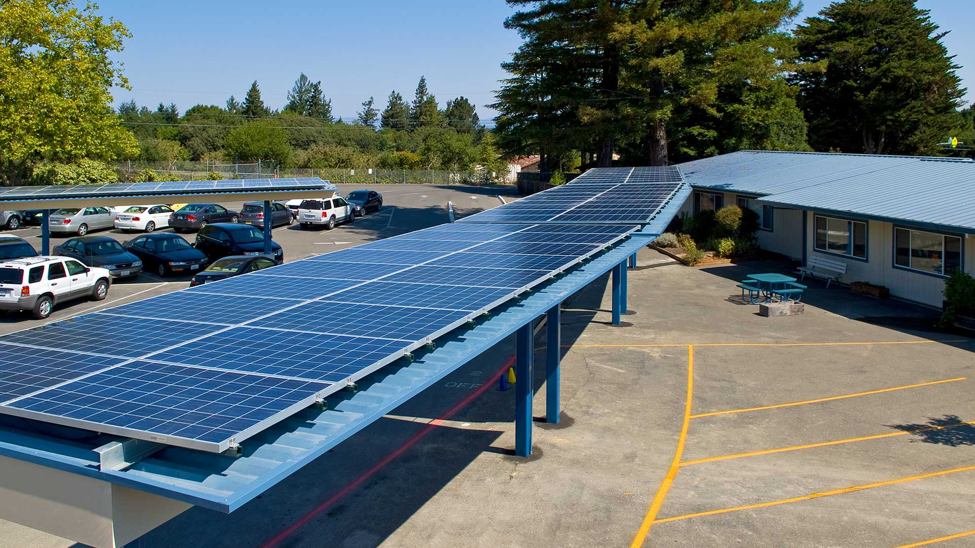 Covered walkways in parking area with solar panels extending along the roof.
