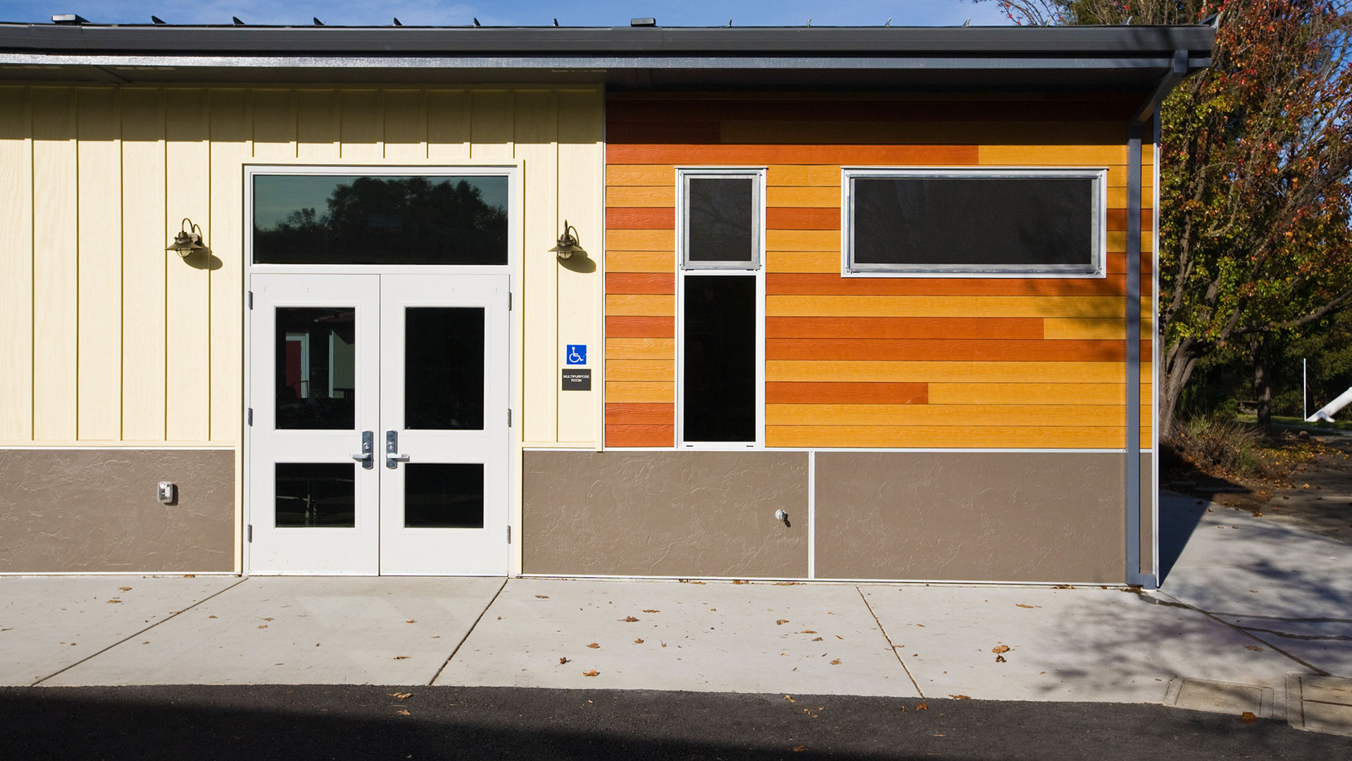 New multi-use room entrance with lighter panels around main doors, and large windows.