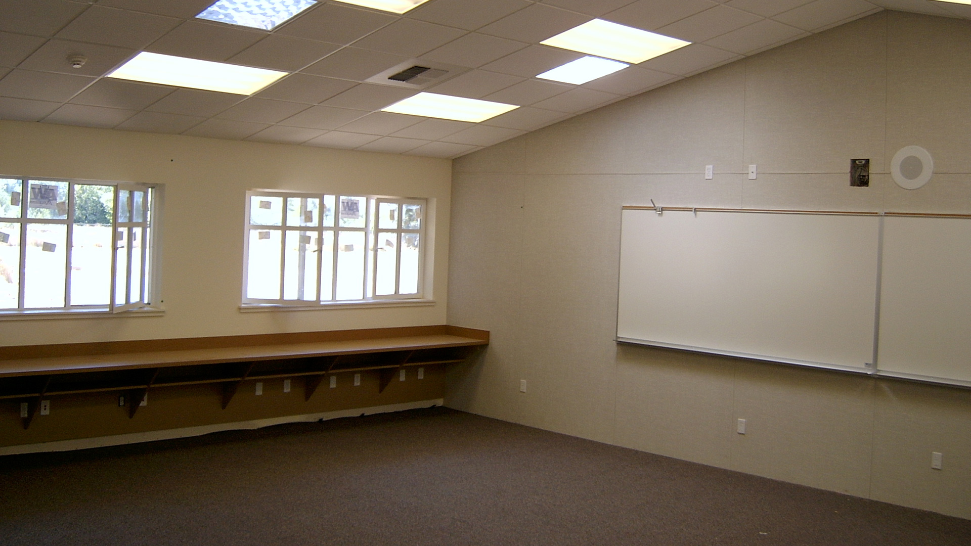 Interior of new classrooms, with vaulted ceilings, operable windows, and brown desks.