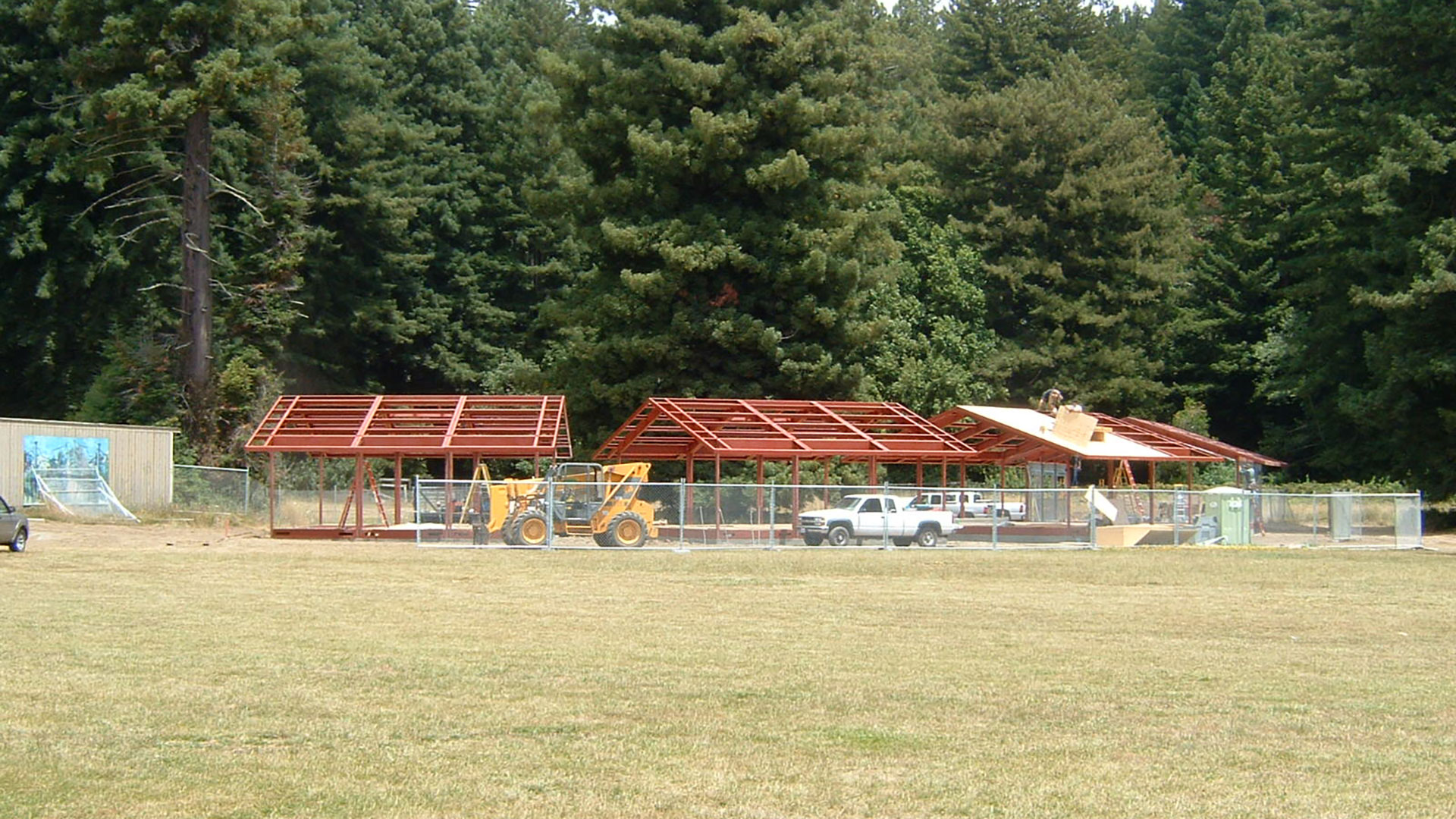 Exposed red metal frame during construction of several buildings side-by-side.