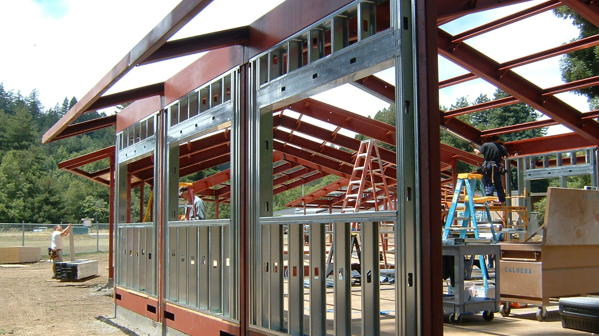 Metal wall and window frames being stalled within the red structural frame.
