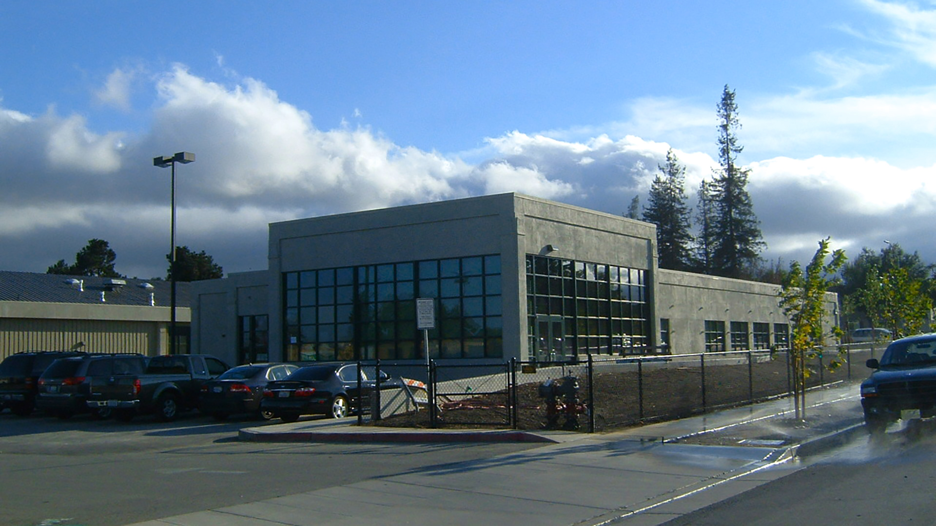 Exterior of district office before landscaping, showing extend of large glass windows around front and side of building.