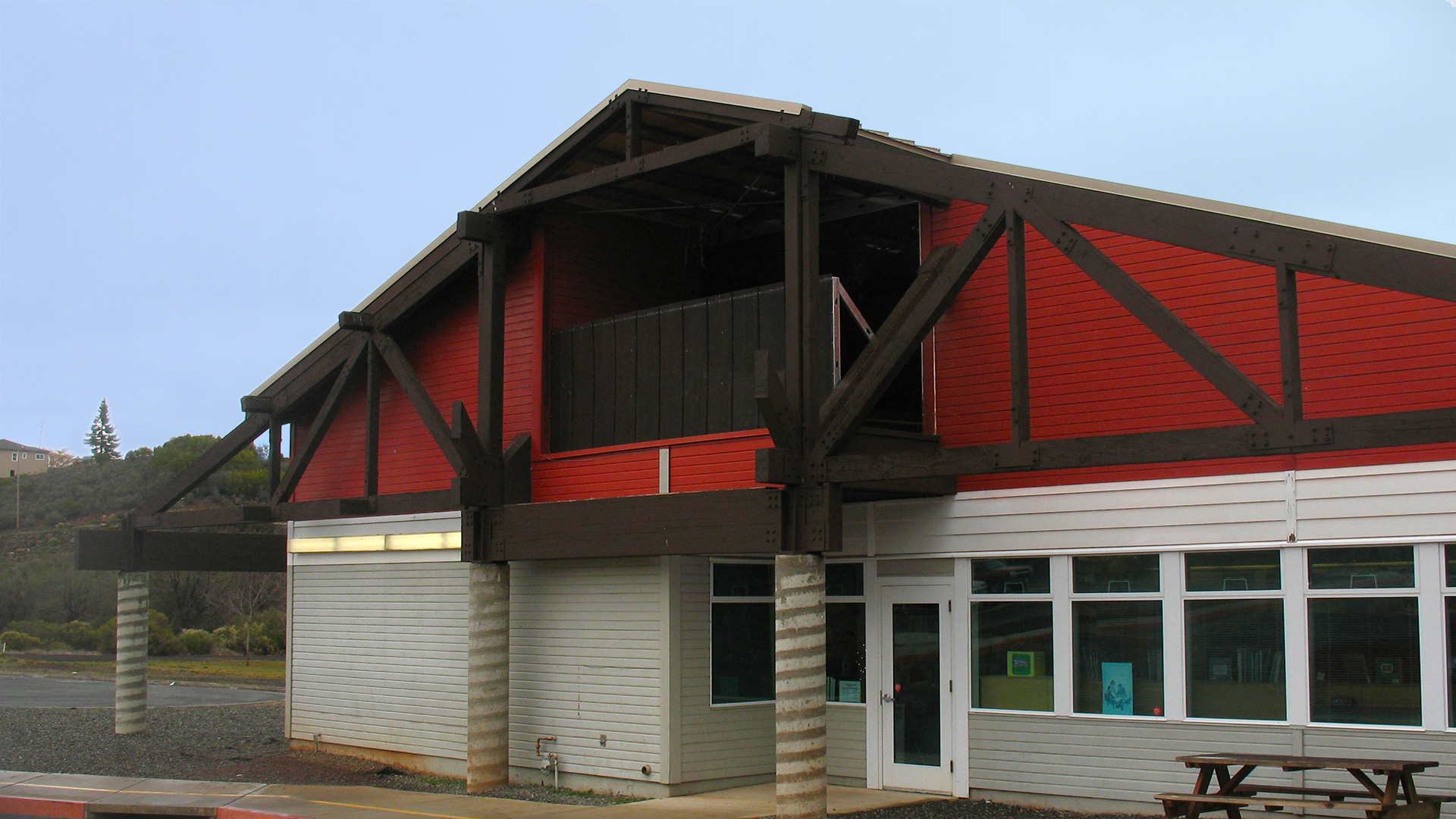 Side of campus building, with red and white walls and exposed brown wooden trusses.